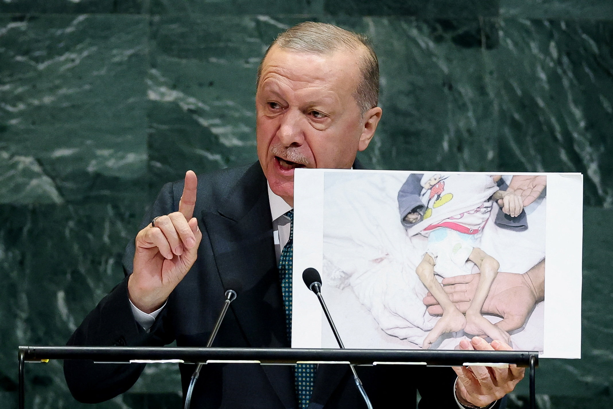 Turkey's President Tayyip Erdogan shows a picture as he addresses