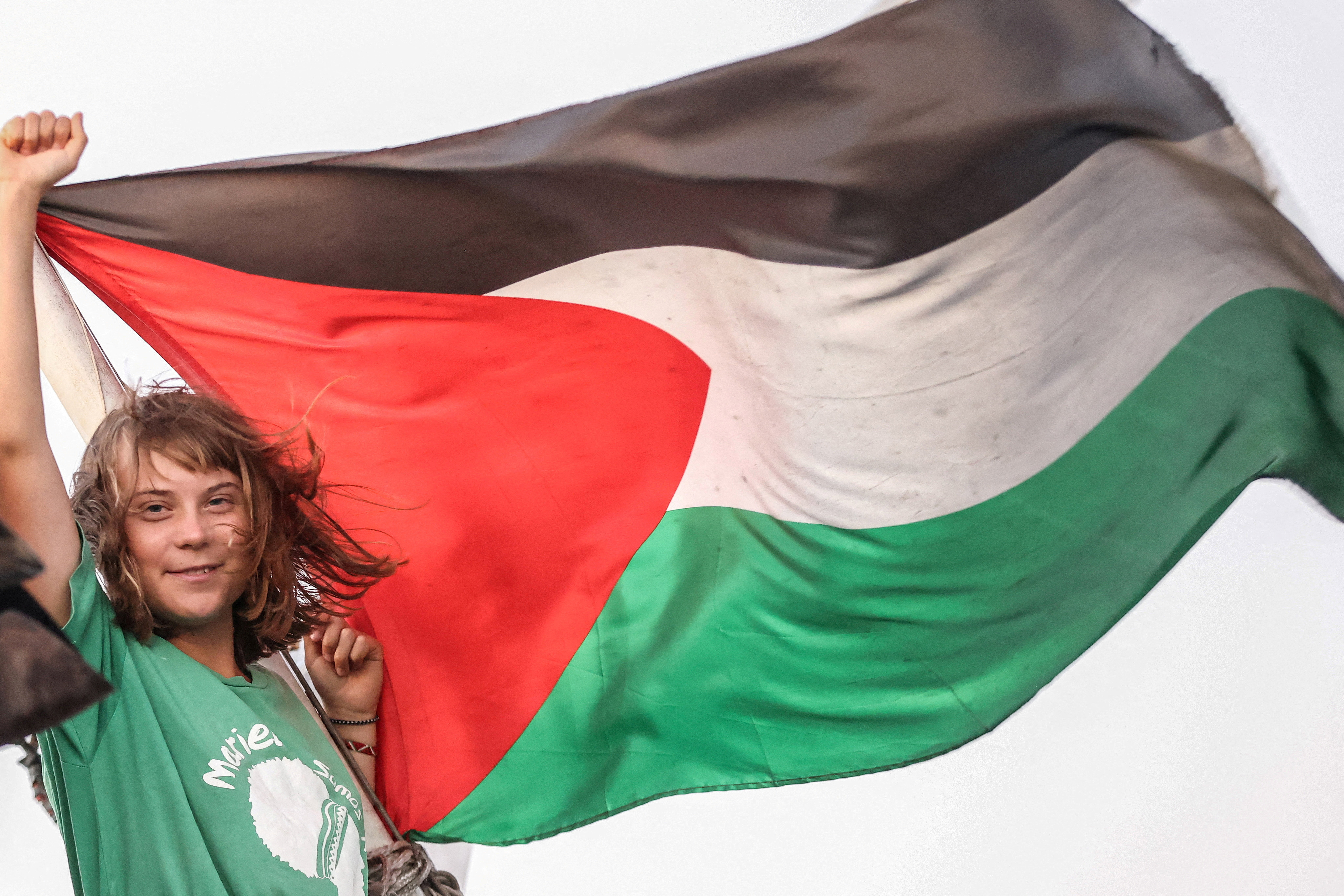 Greta Thunberg gestures next to a Palestinian flag on a ship