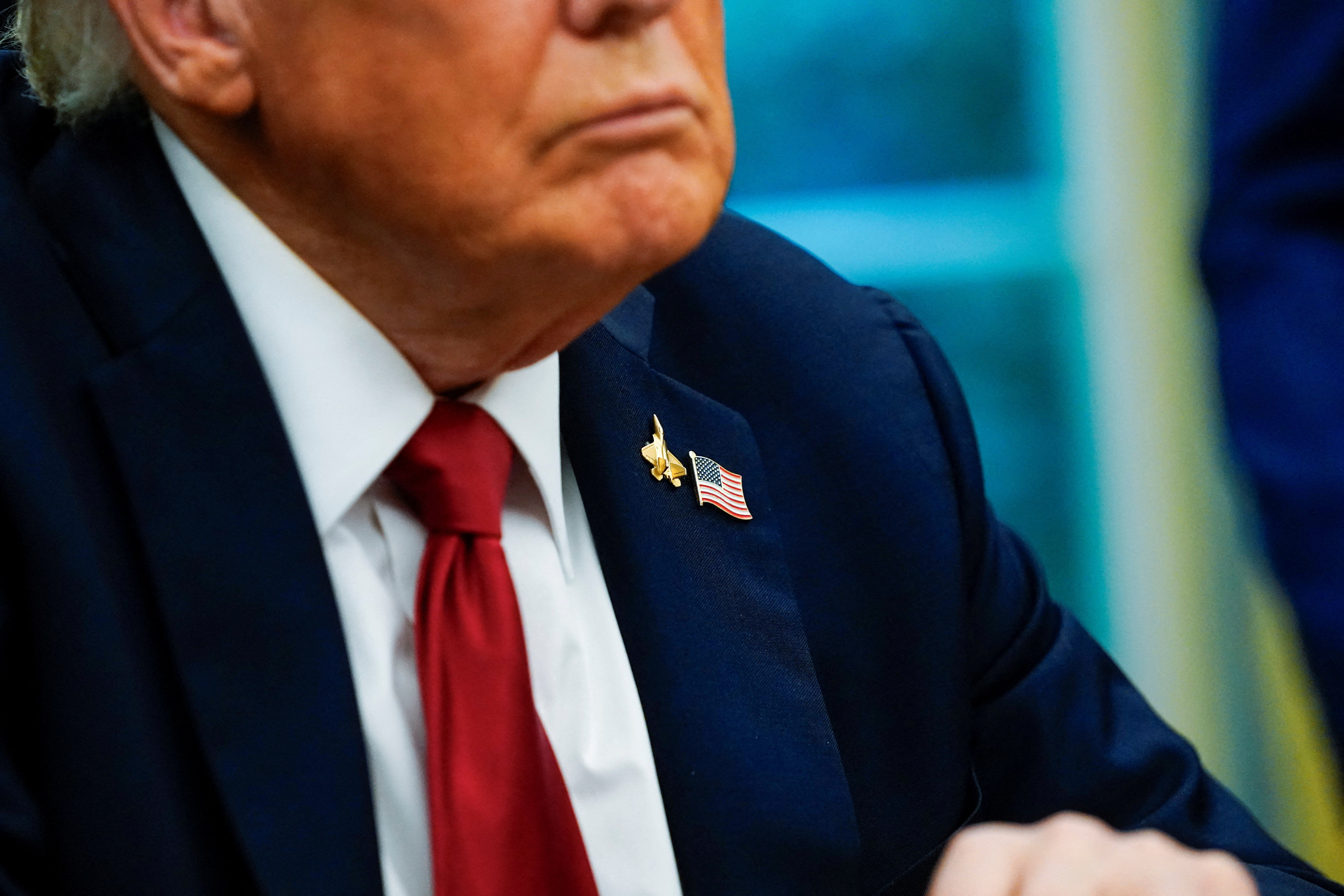 U.S. President Donald Trump wears a fighter jet and a U.S. flag pins in the Oval Office