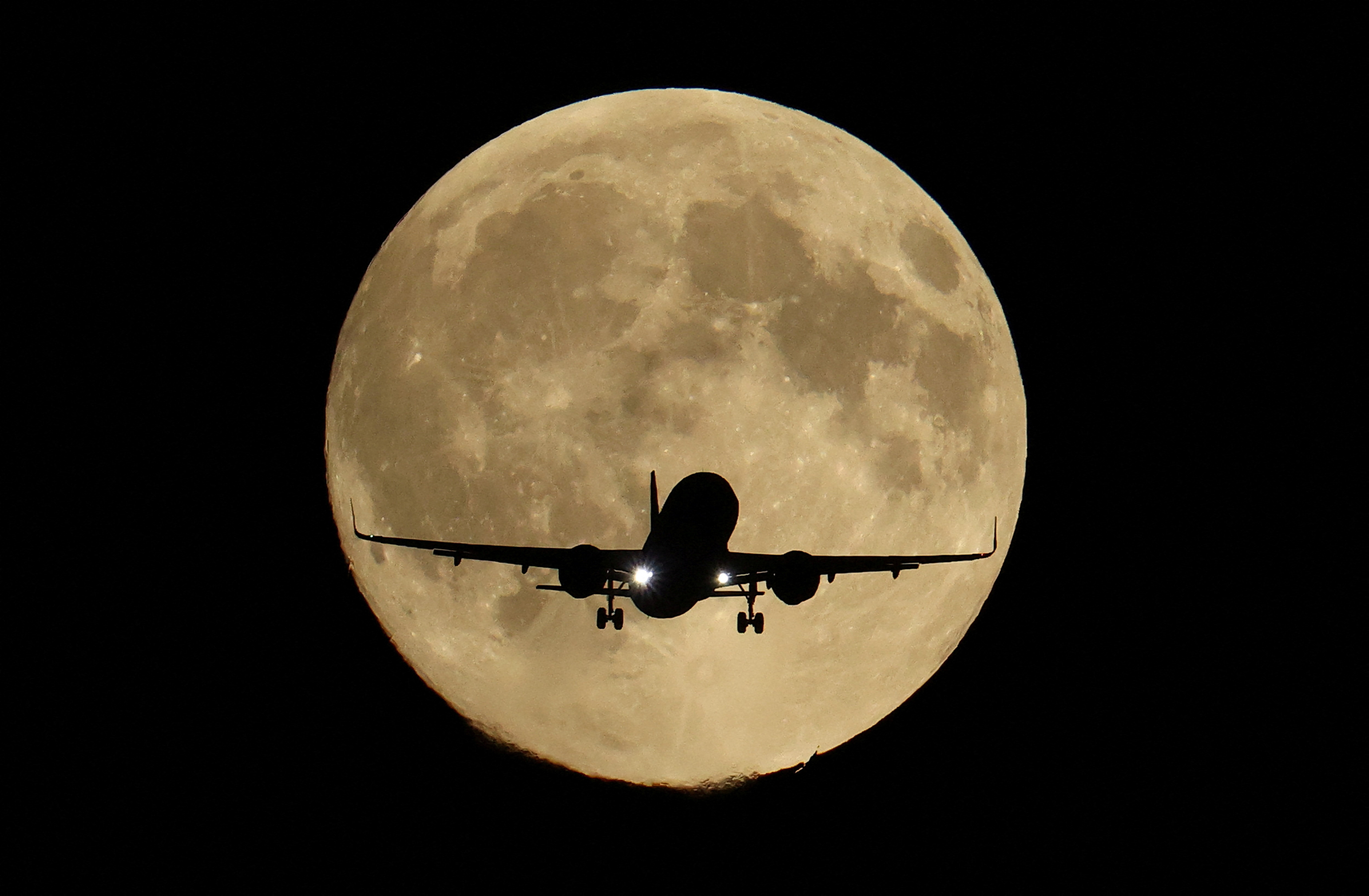 A passenger plane passes in front of the first supermoon of the year, known as the Harvest Moon, as it flies above London, Britain, October 6, 2025. REUTERS/Toby Melville     TPX IMAGES OF THE DAY