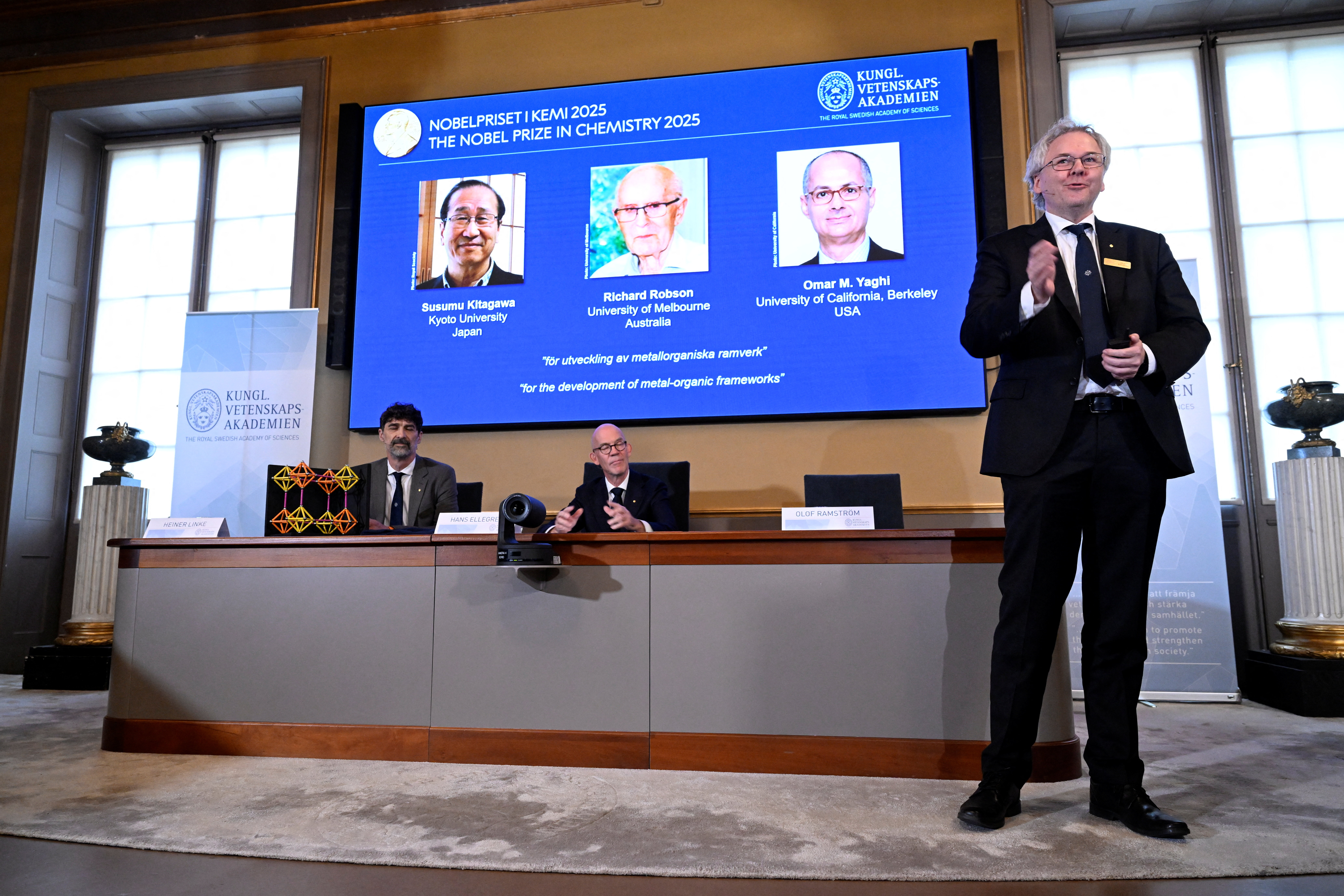 A screen displays the 2025 Nobel Prize laureates in Chemistry