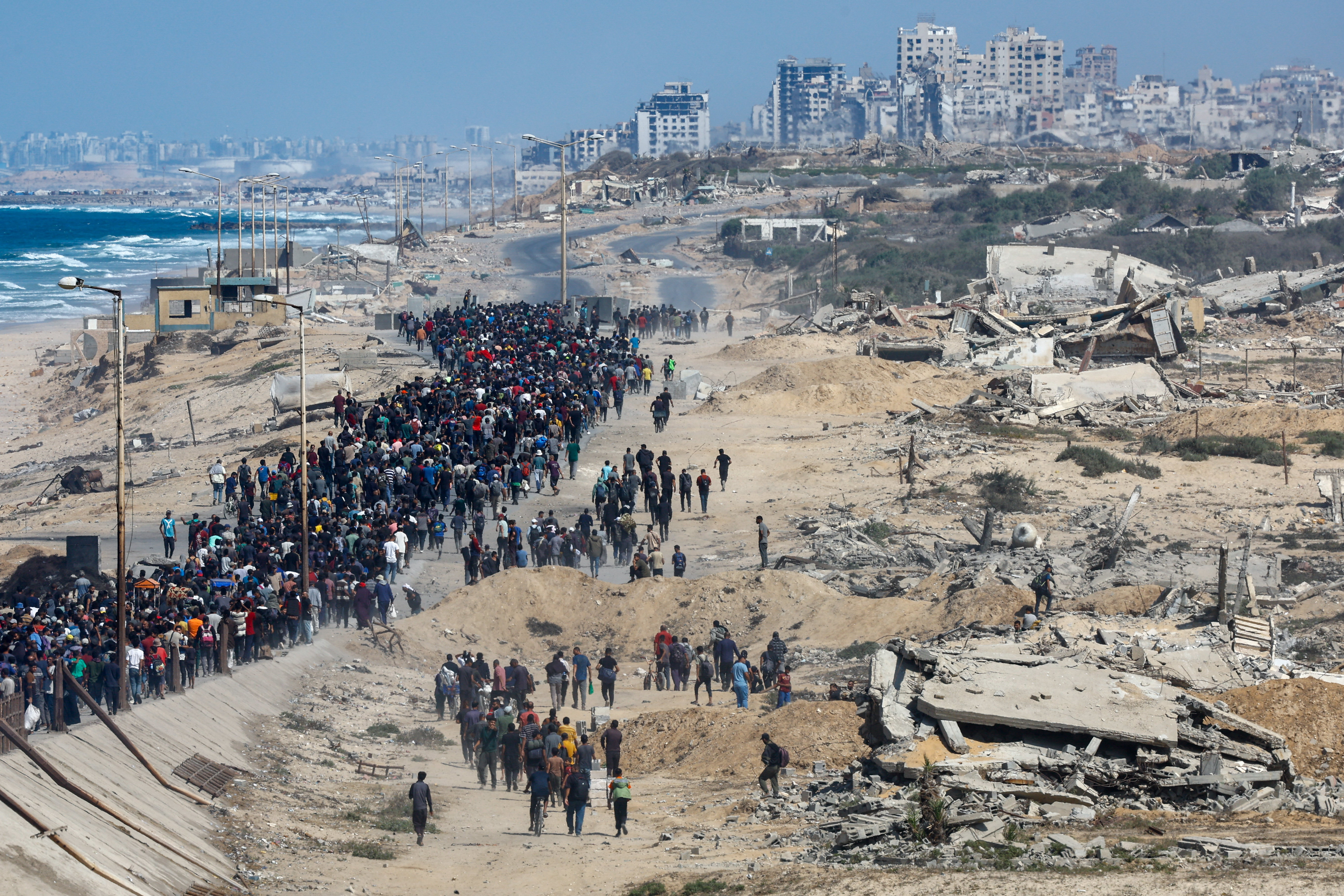 Palestinians, who were displaced to the southern part of Gaza at Israel's order during the war, walk along a road ast destroyed buildings as they attempt to return to the north after a ceasefire