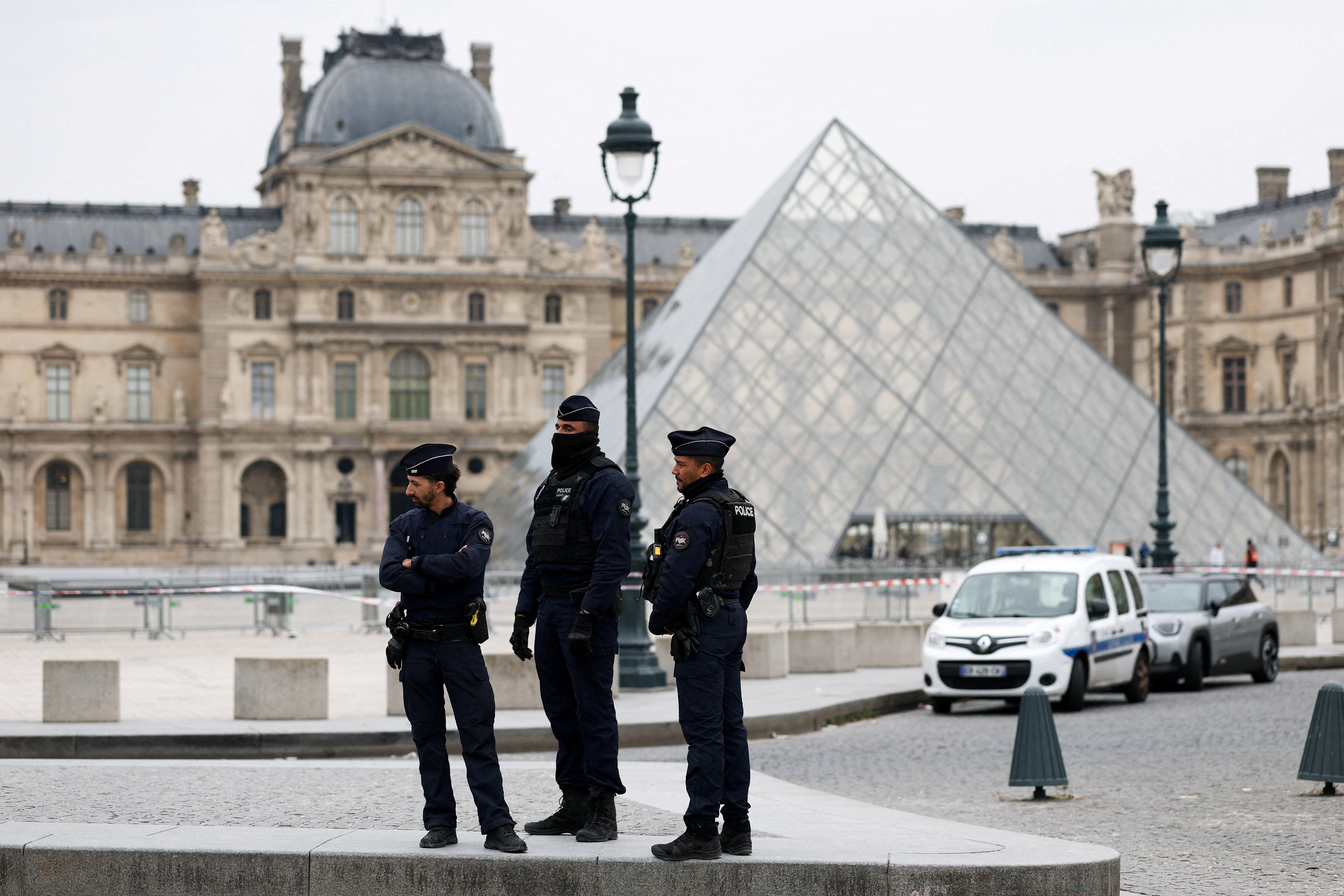 Police officers stand near the pyramid of the Louvre museum after reports of a robbery