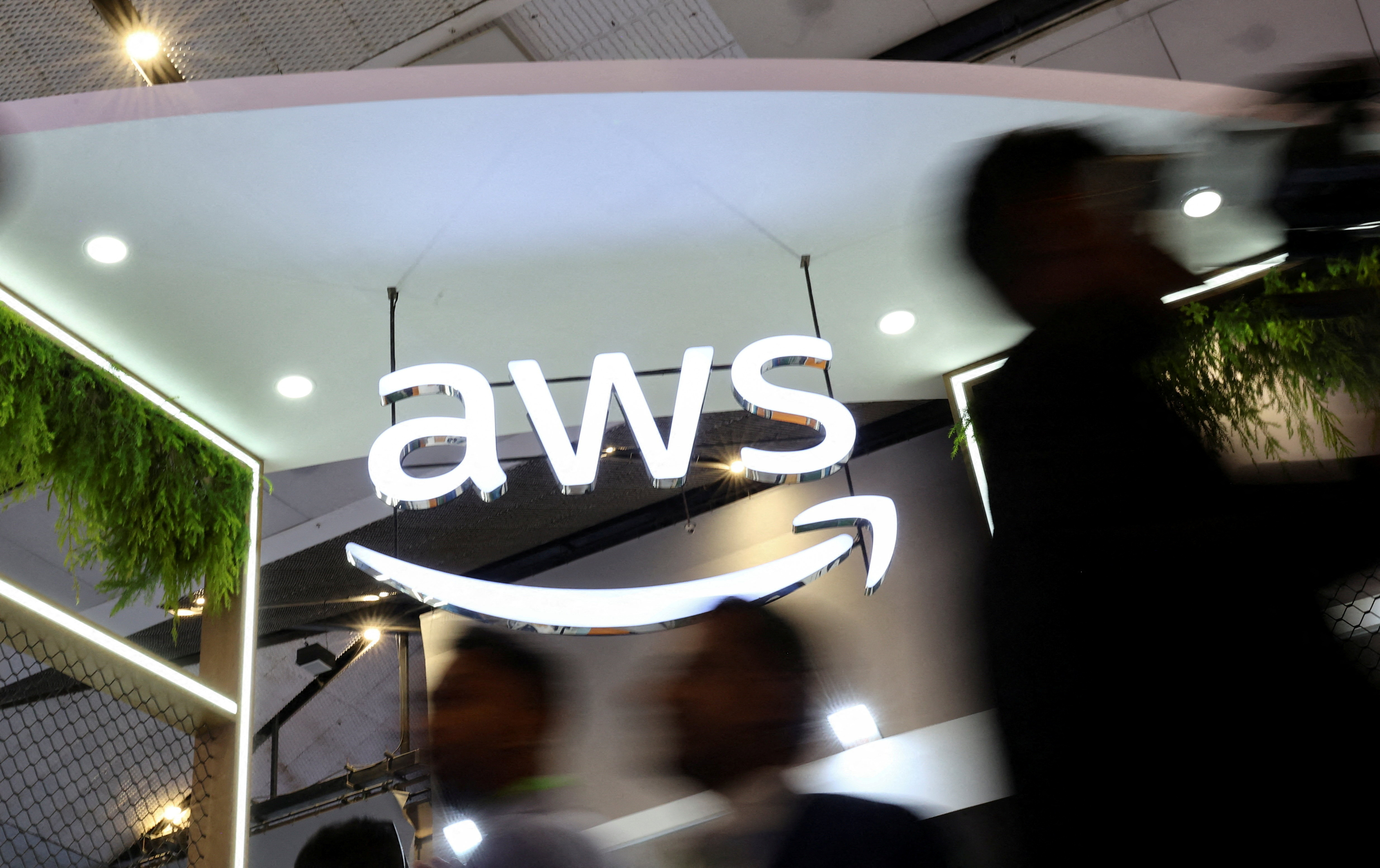 FILE PHOTO: People walk past the logo of Amazon Web Services (AWS)