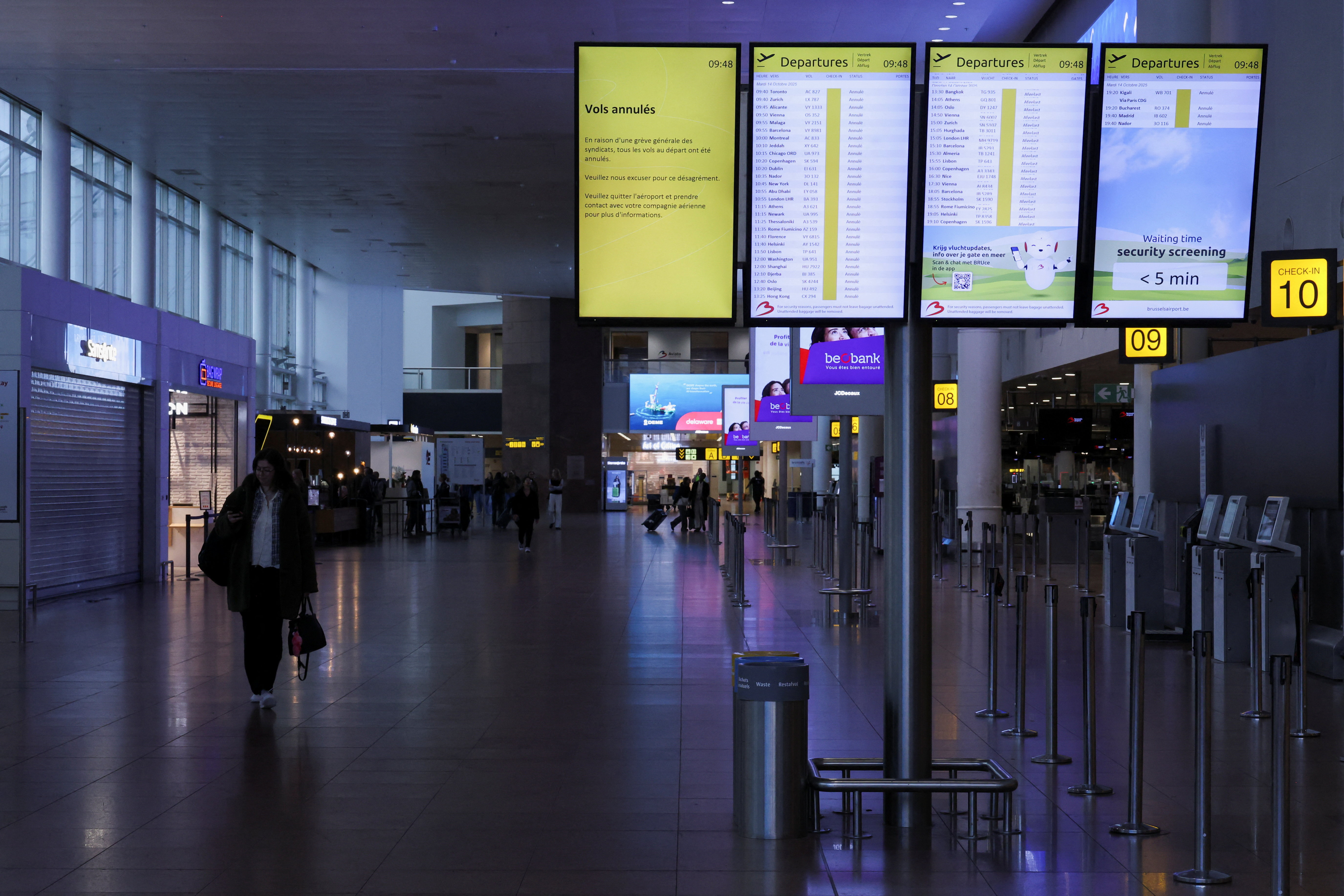 A passenger walks near a board displaying information on cancelled flights, during a nationwide strike against the government's reform plans, at Brussels Airport in Zaventem near Brussels, Belgium October 14, 2025.  REUTERS/Omar Havana