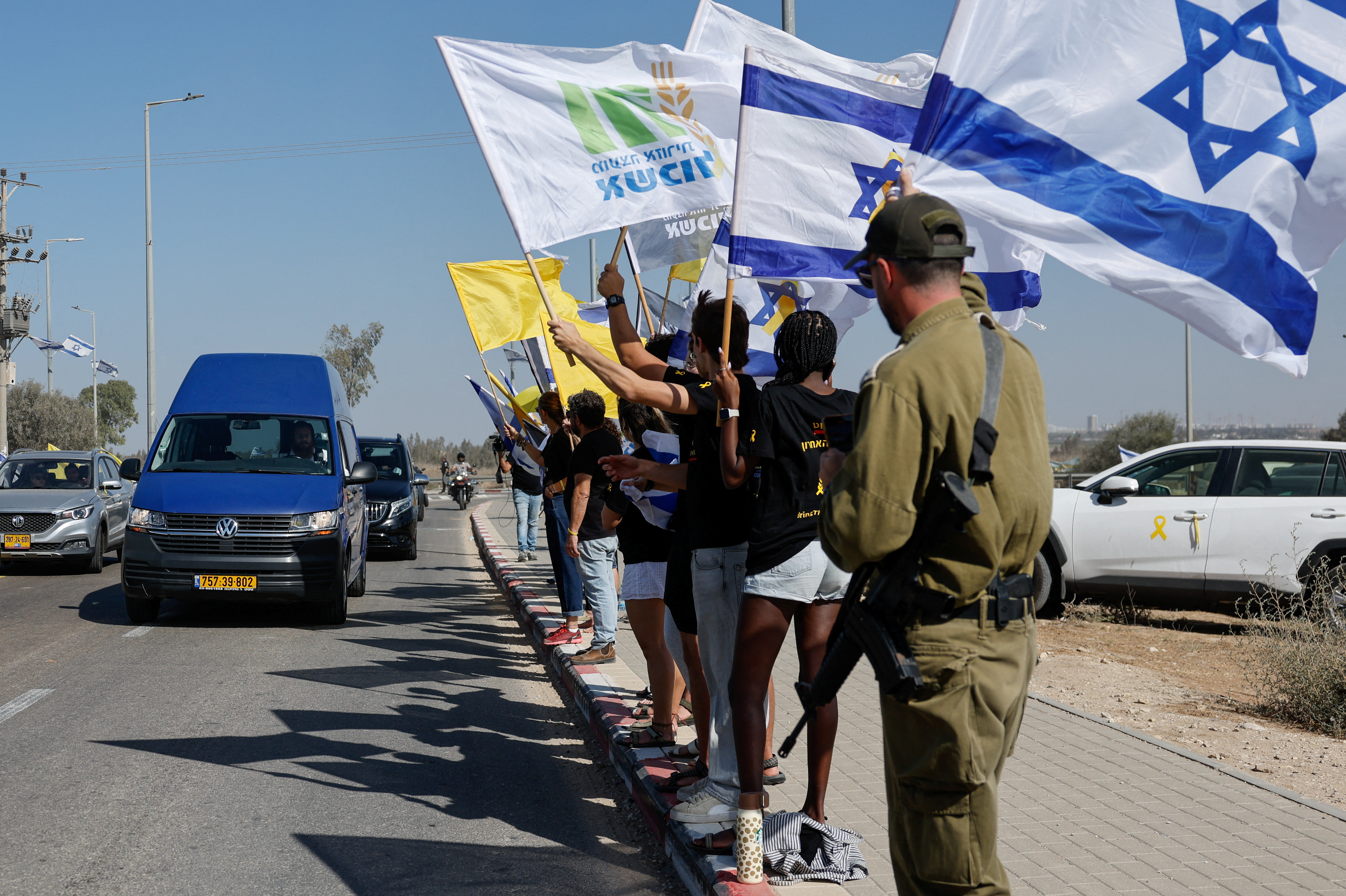 Mourners wave flags as a vehicle carries the body of Israeli hostage Yossi Sharabi, who, according to the Hostages Families Forum, was abducted alive and killed in captivity