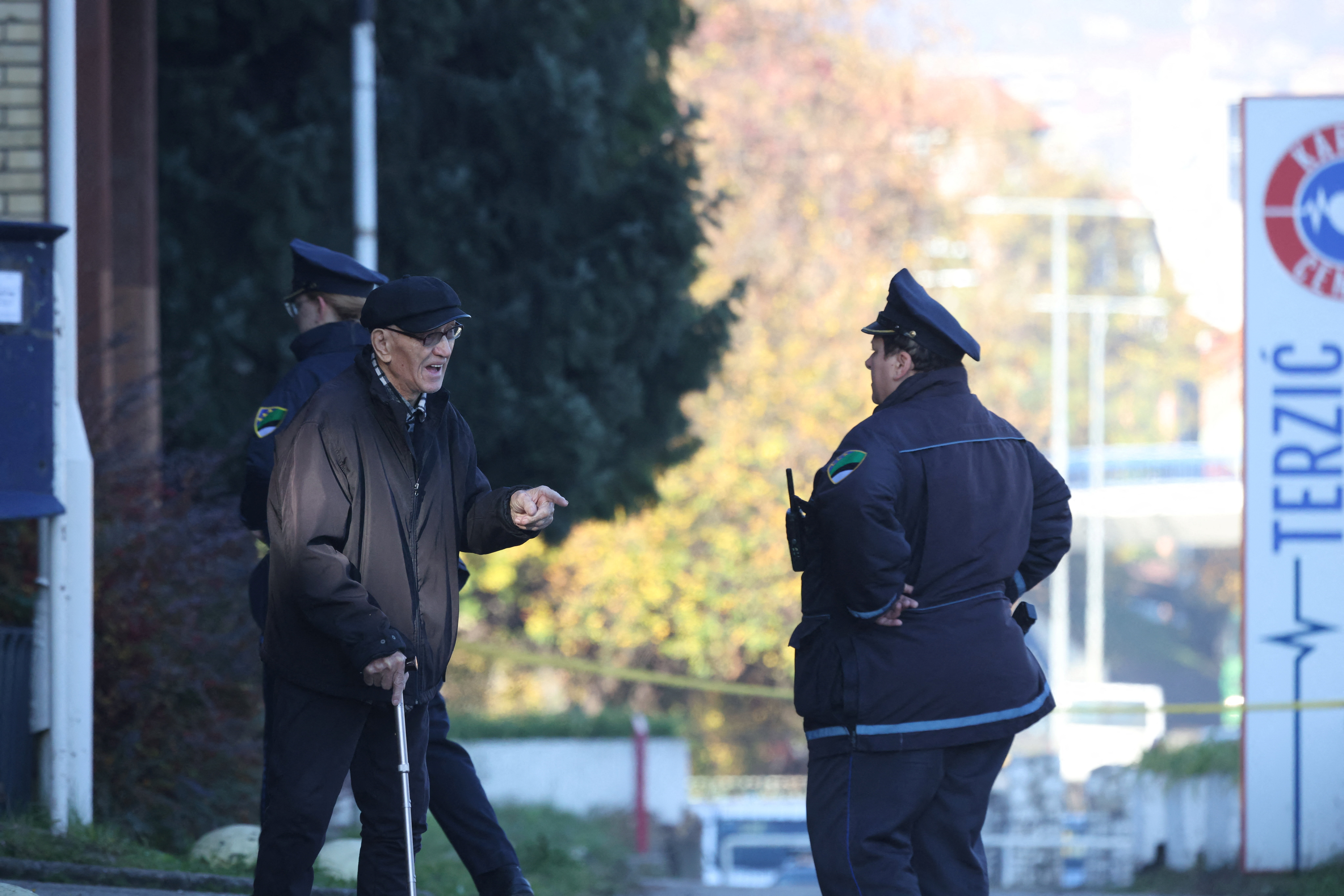 An elderly man talks to a police officer in front of the building of a home for the elderly where a fire broke out, in the town of Tuzla