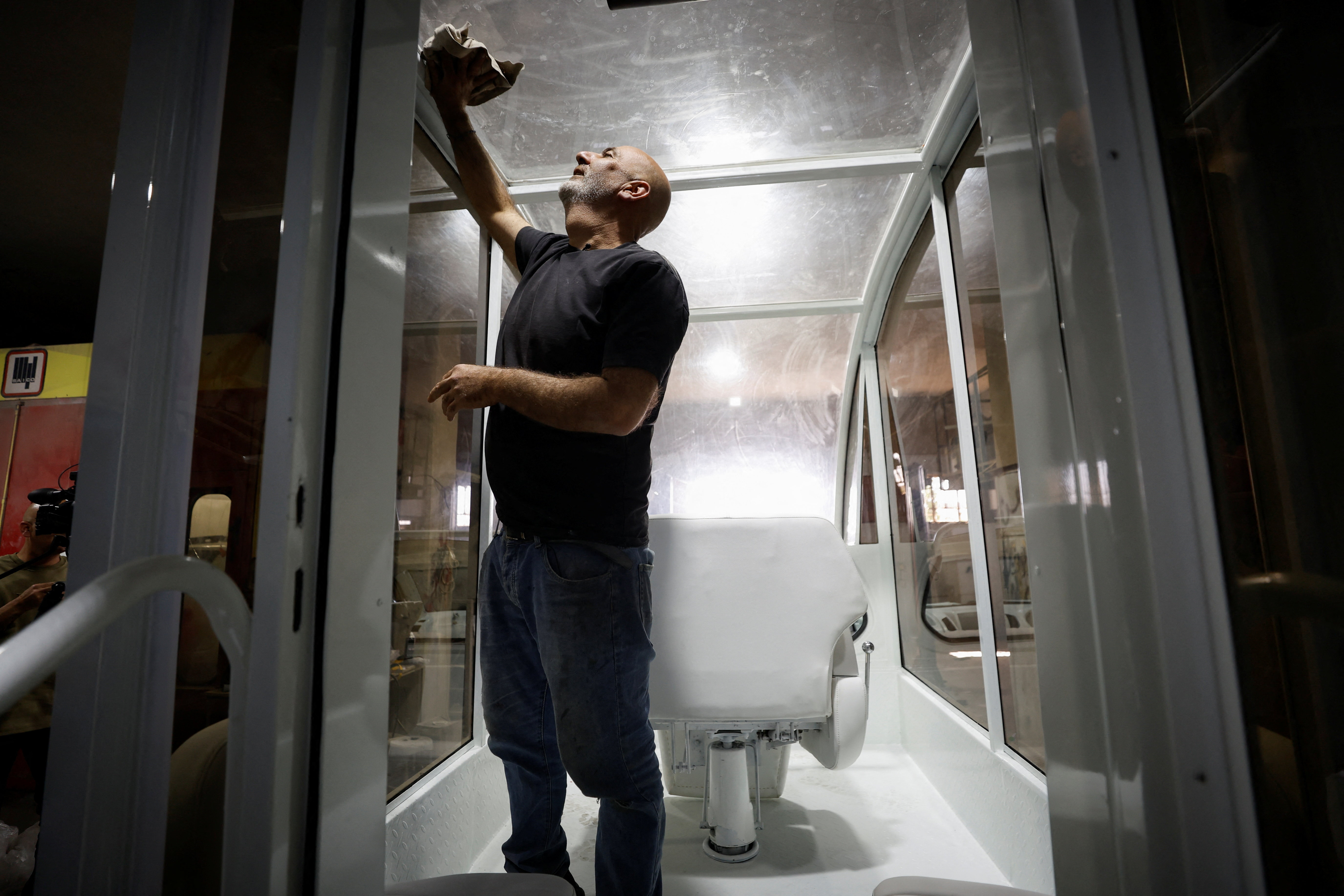 A Palestinian cleans the Vehicle of Hope, the former popemobile used by Pope Francis during its transformation into a fully equipped mobile clinic, in Bethlehem in the Israeli-occupied West Bank, May 20, 2025. REUTERS/Mussa Qawasma