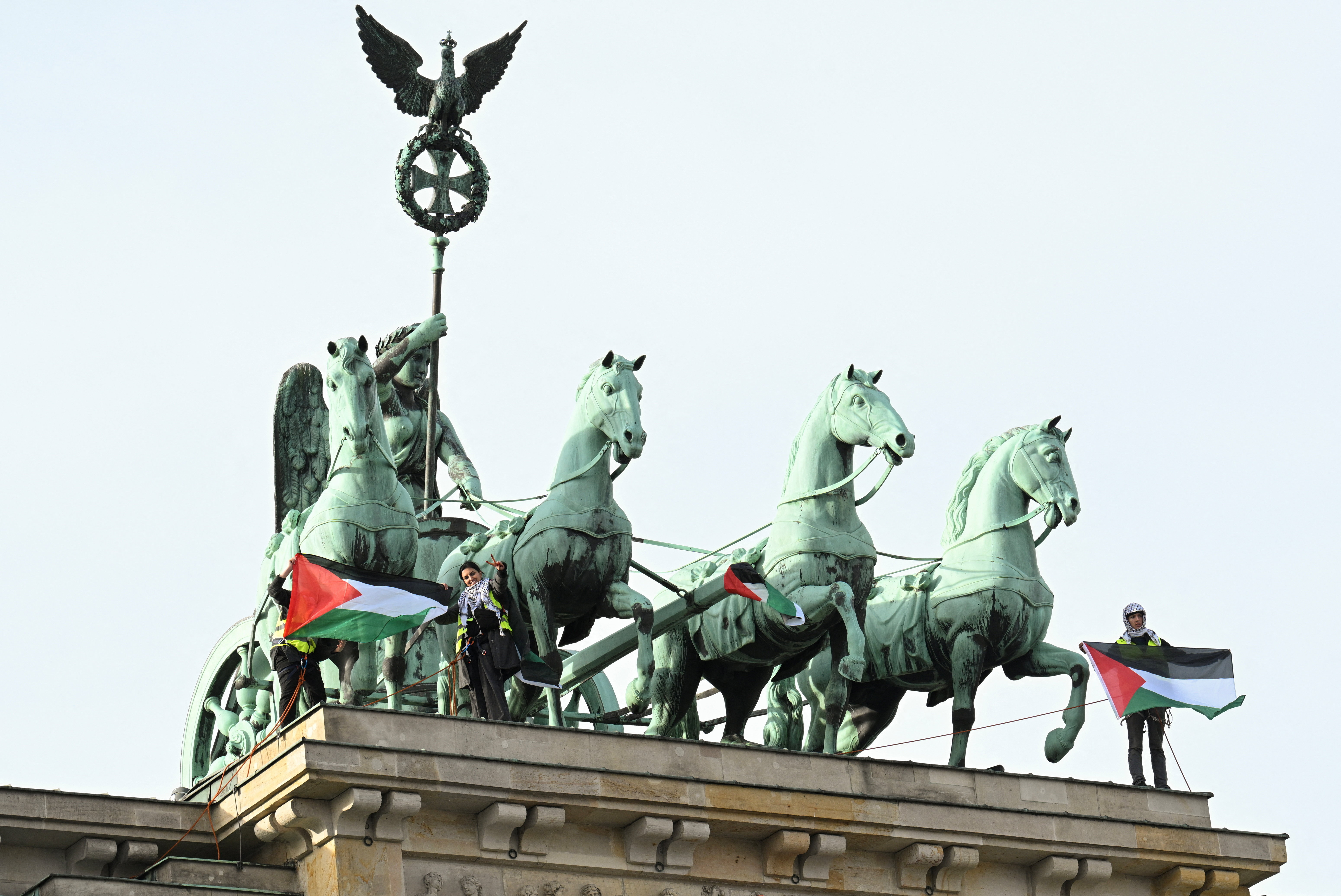 Pro-Palestinian protesters present flags of Palestine after unveiling a banner reading, “Never again genocide - Freedom for Palestine”, on top of Brandenburg Gate in Berlin, Germany, November 13, 2025.   REUTERS/Annegret Hilse