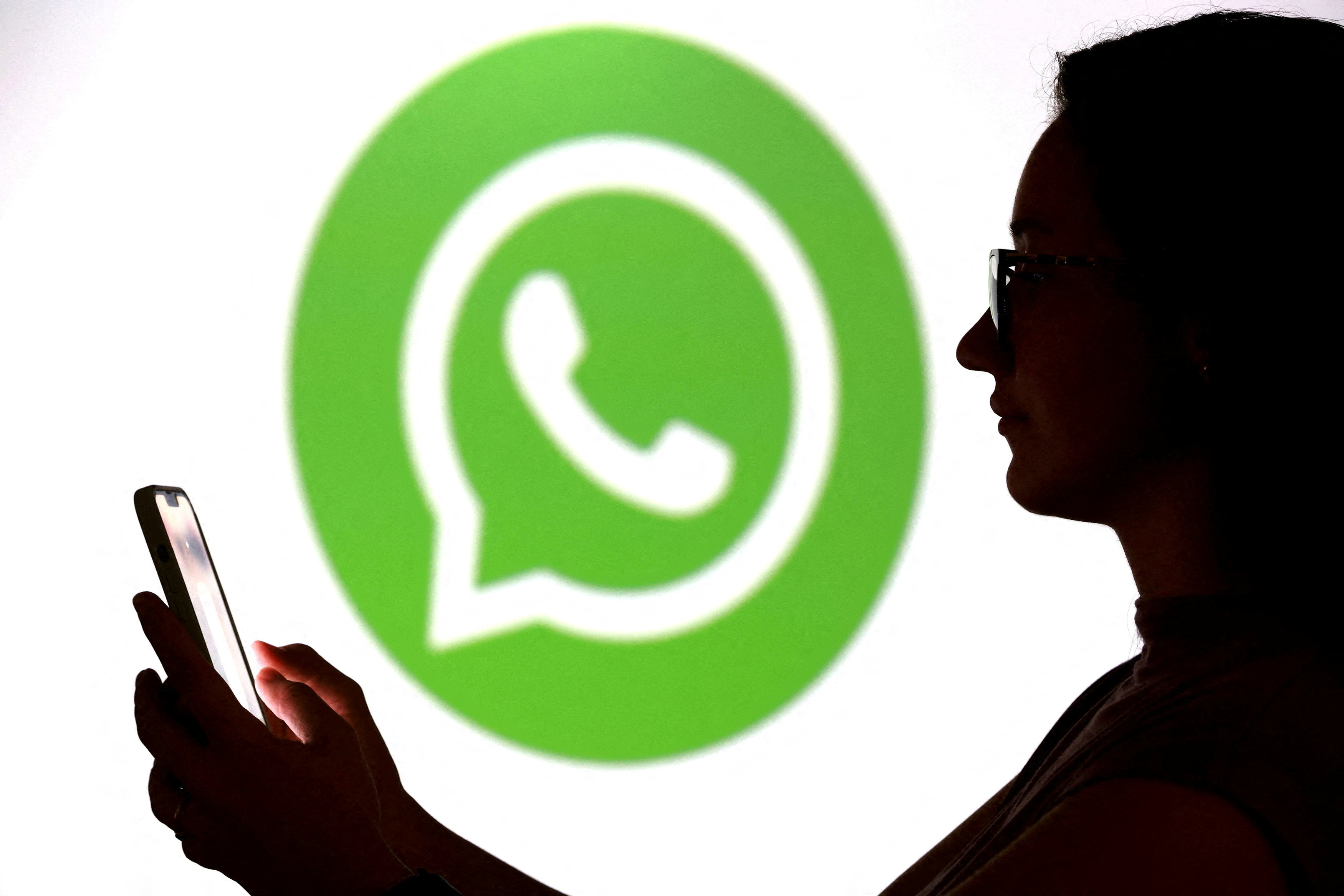 FILE PHOTO: A teenager poses for a photo while holding a smartphone in front of a Whatsapp logo in this illustration taken September 11, 2025. REUTERS/Dado Ruvic/Illustration/File Photo