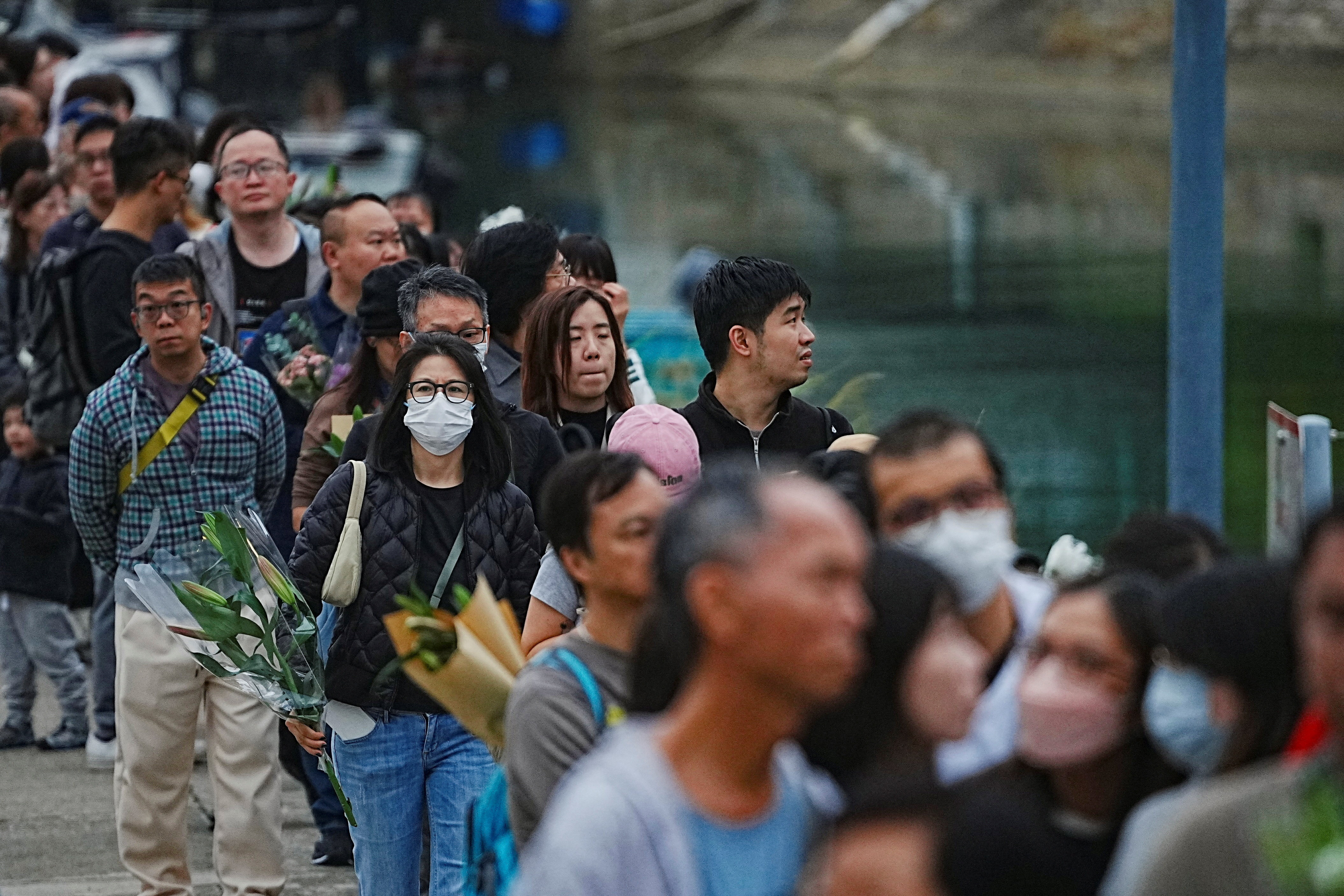 People queue to place flowers at a makeshift memorial near Wang Fuk Court housing estate to pay tribute to victims of the deadly fire at the Wang Fuk Court housing complex, in Tai Po, Hong Kong, China, November 30, 2025. REUTERS/Lam Yik