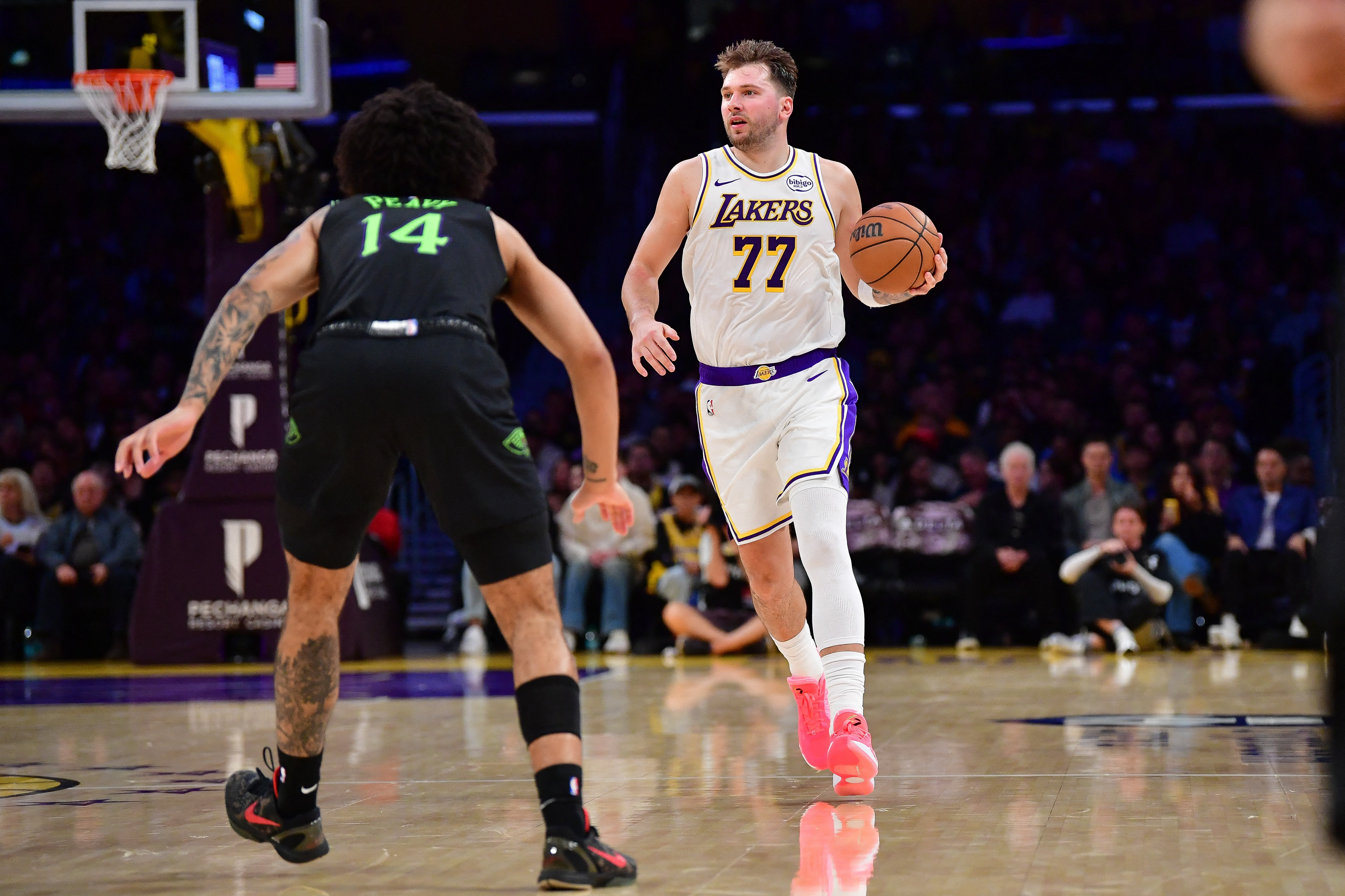 Nov 30, 2025; Los Angeles, California, USA; Los Angeles Lakers guard Luka Doncic (77) controls the ball against New Orleans Pelicans guard Micah Peavy (14) during the first half at Crypto.com Arena. Mandatory Credit: Gary A. Vasquez-Imagn Images