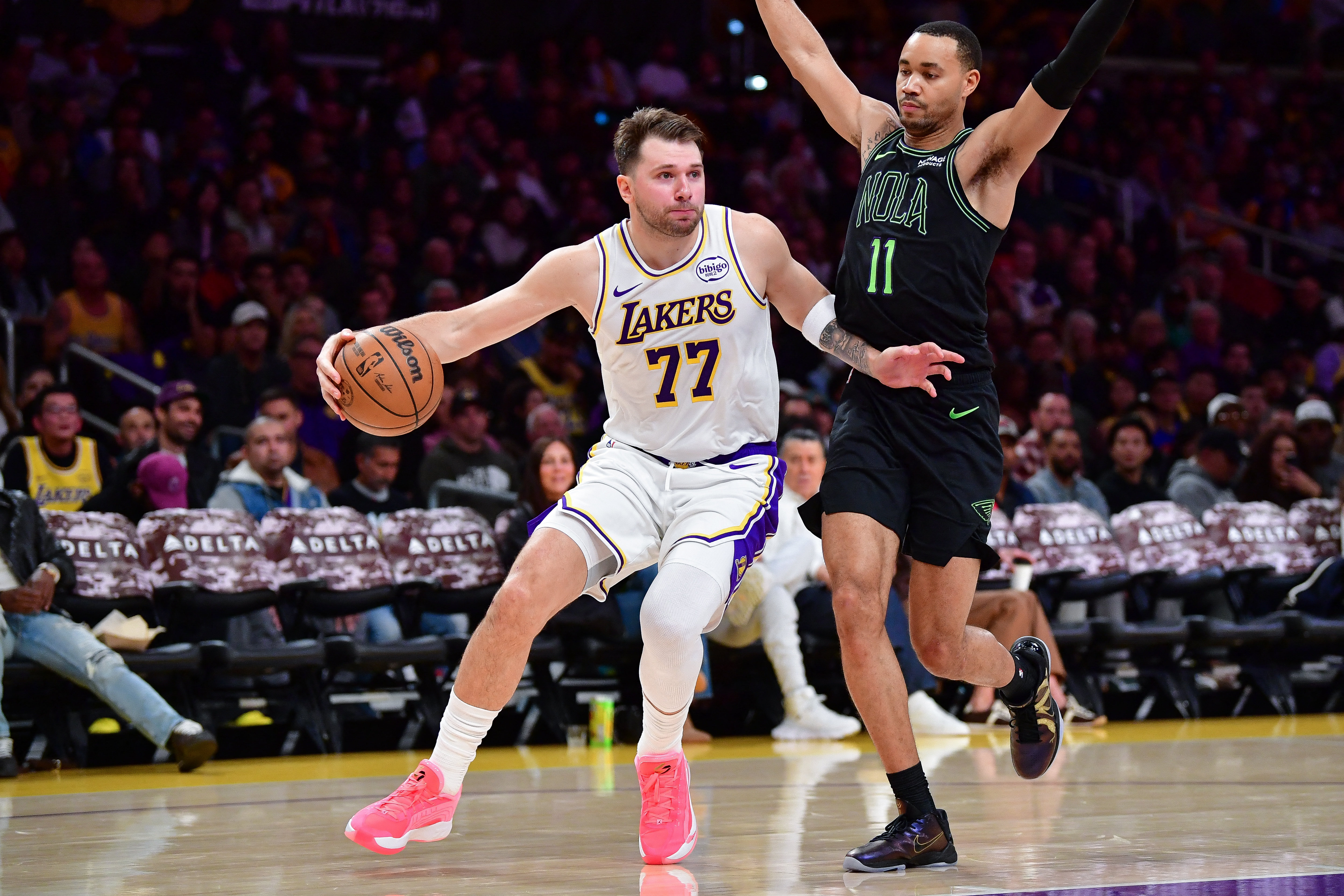 Nov 30, 2025; Los Angeles, California, USA; Los Angeles Lakers guard Luka Doncic (77) moves the ball against New Orleans Pelicans guard Bryce McGowens (11) during the first half at Crypto.com Arena. Mandatory Credit: Gary A. Vasquez-Imagn Images
