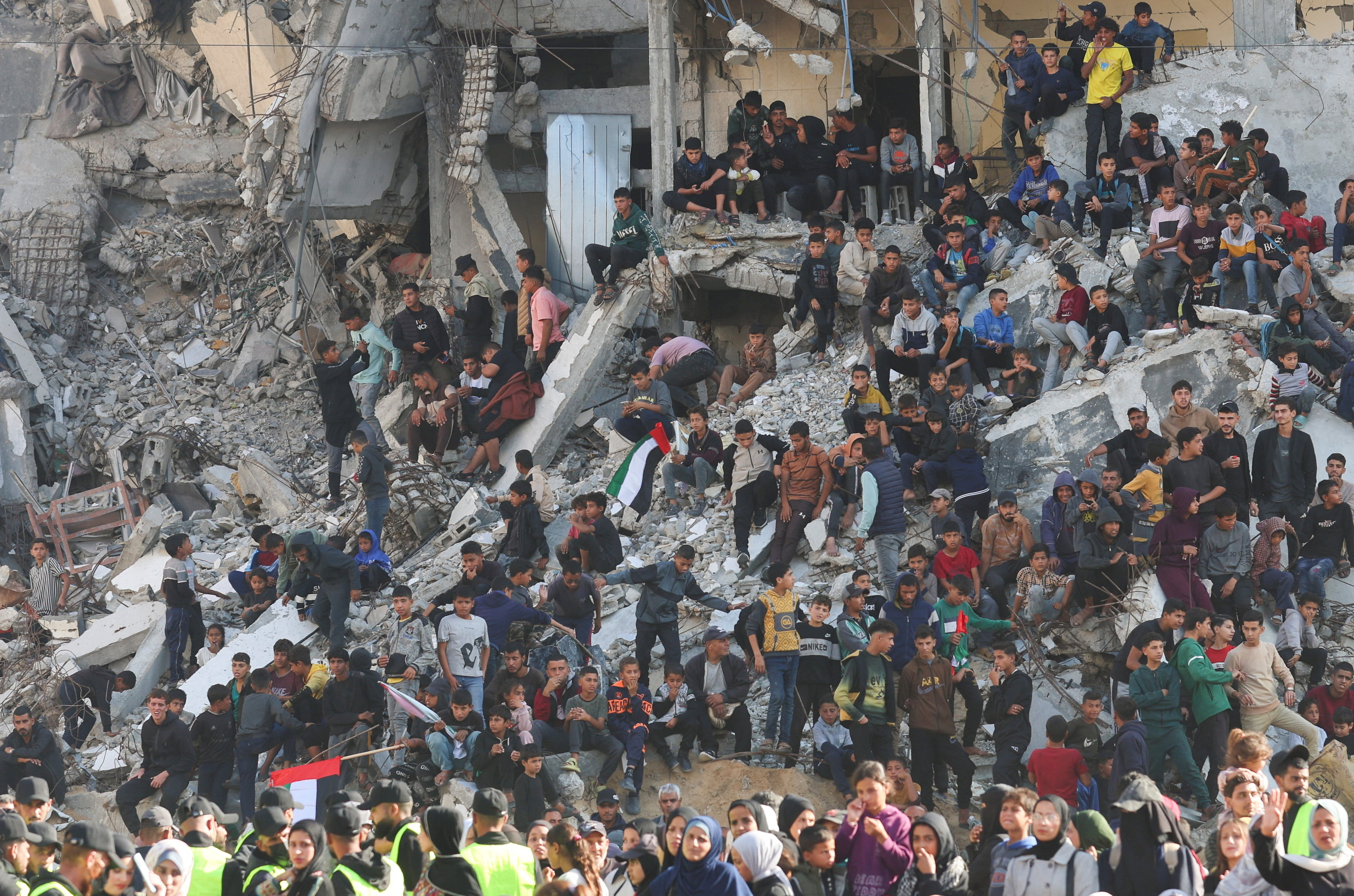 People gather amid damaged buildings to watch a mass wedding for 54 Palestinian couples in Khan Younis, in the southern Gaza Strip December 2, 2025. REUTERS/Ramadan Abed