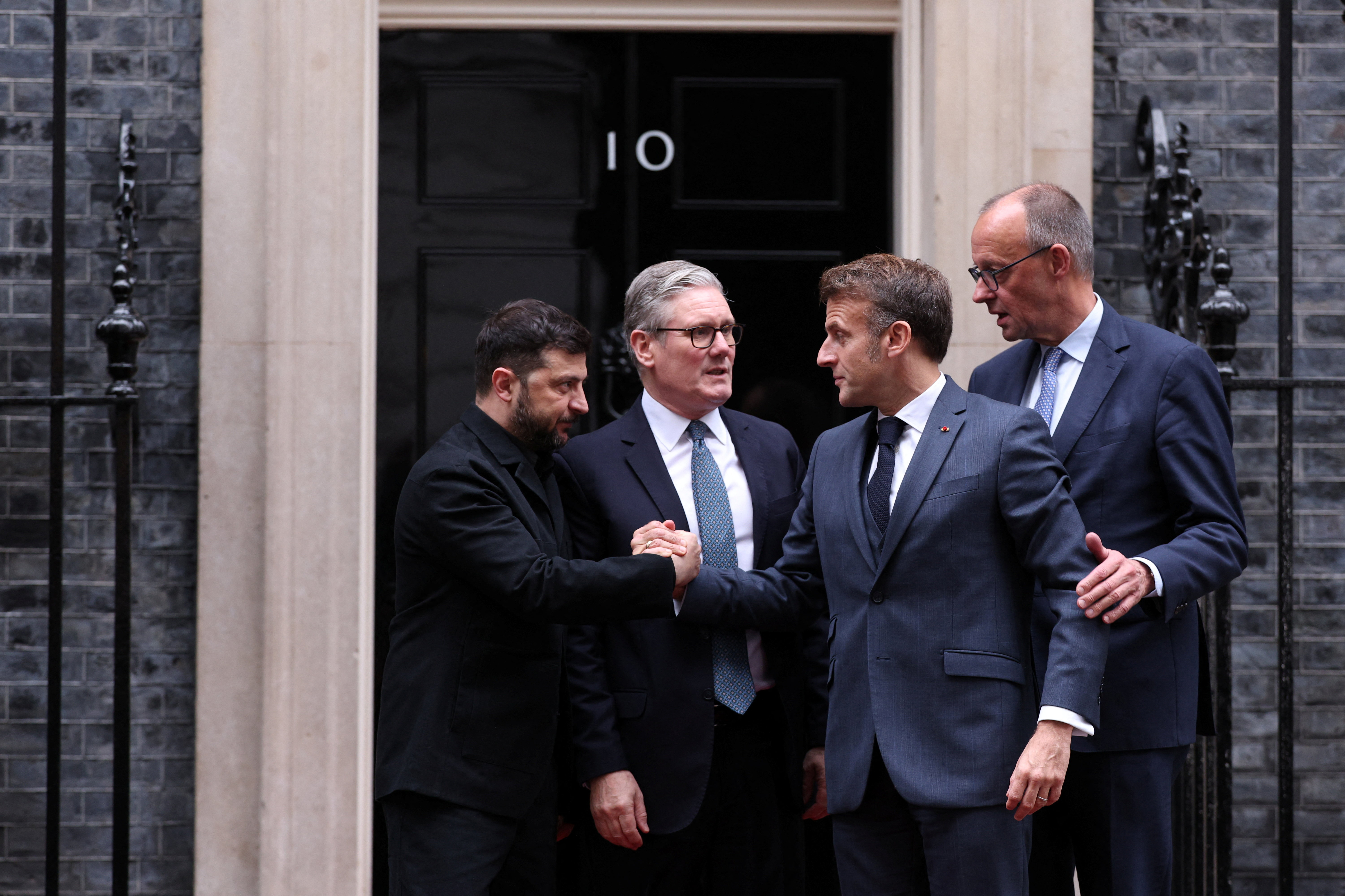Volodymyr Zelenskiy and Emmanuel Macron shake hands on the 10 Downing Street doorstep after a meeting with Keir Starmer and  Friedrich Merz, in London, Britain, December 8, 2025.  ADRIAN DENNIS/Pool via REUTERS