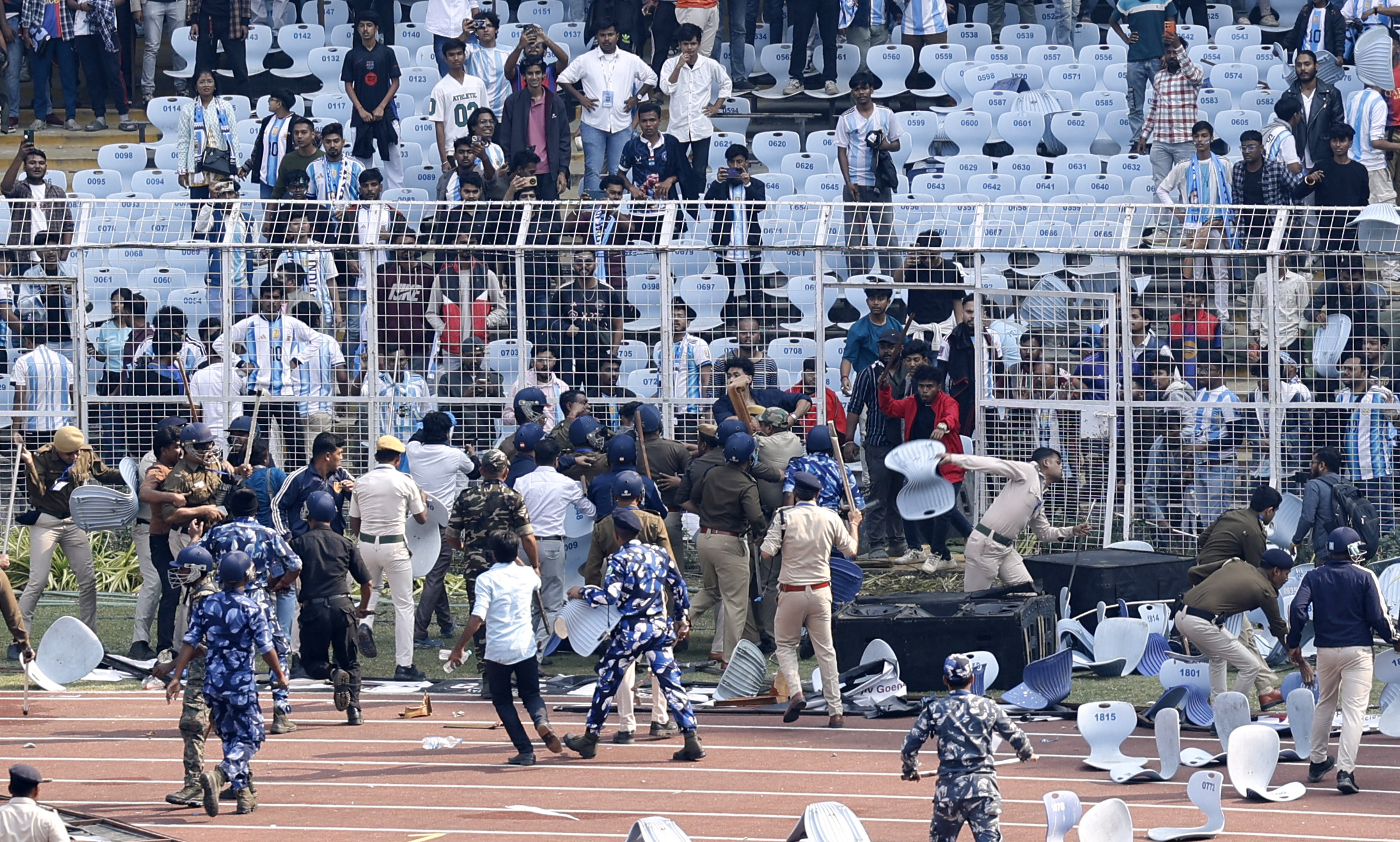 Soccer Football - Argentine soccer star Lionel Messi on a whirlwind tour of India - Vivekananda Yuva Bharati Krirangan, Kolkata, India - December 13, 2025 Riot police and fans are seen on the pitch after Argentine soccer star Lionel Messi leaves the stadi