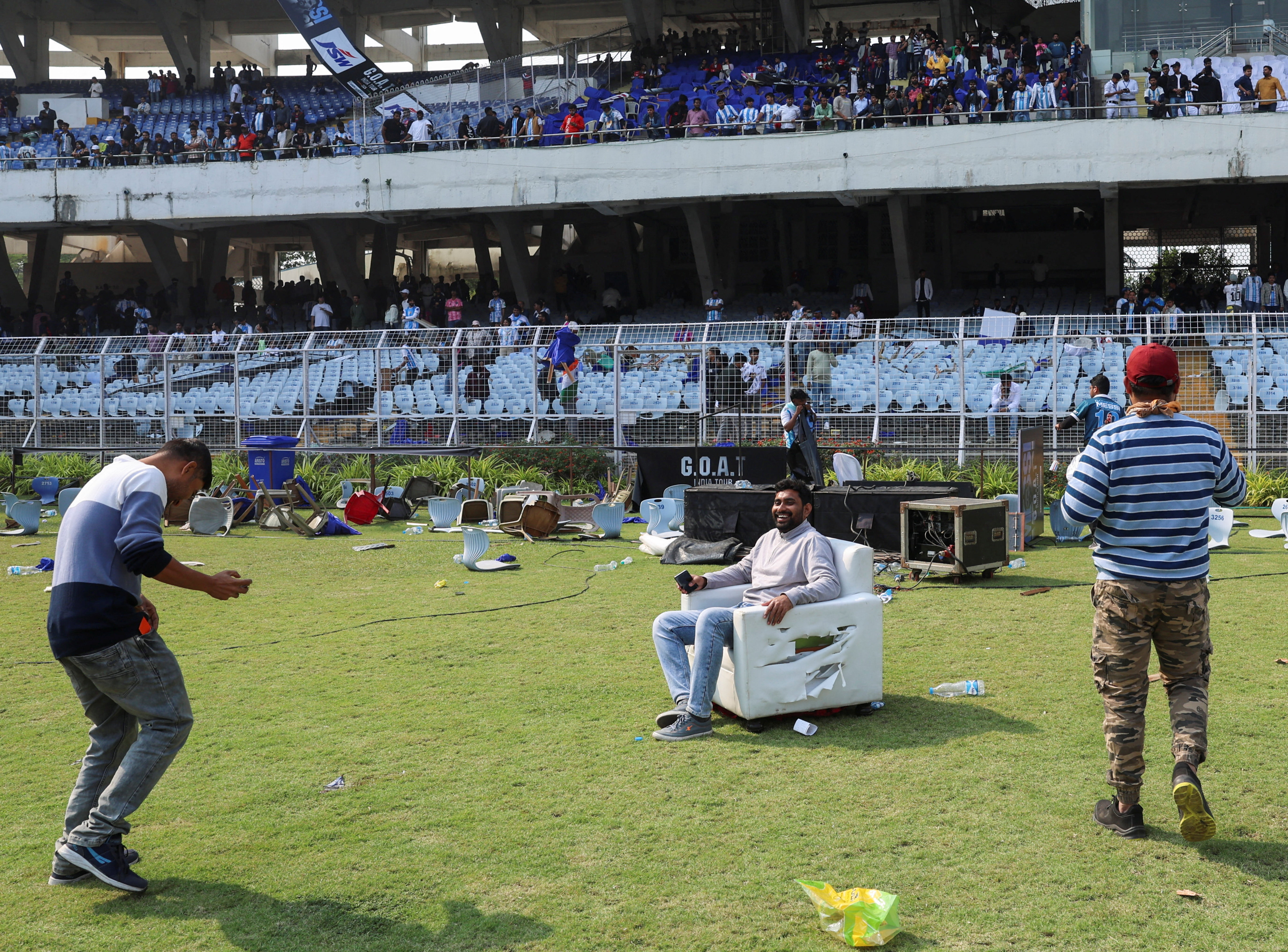A fan poses for a picture while sitting on a damaged sofa after Argentine soccer star Lionel Messi left the Vivekananda Yuva Bharati Krirangan stadium during his India tour, Kolkata, India, December 13, 2025. REUTERS/Sahiba Chawdhary