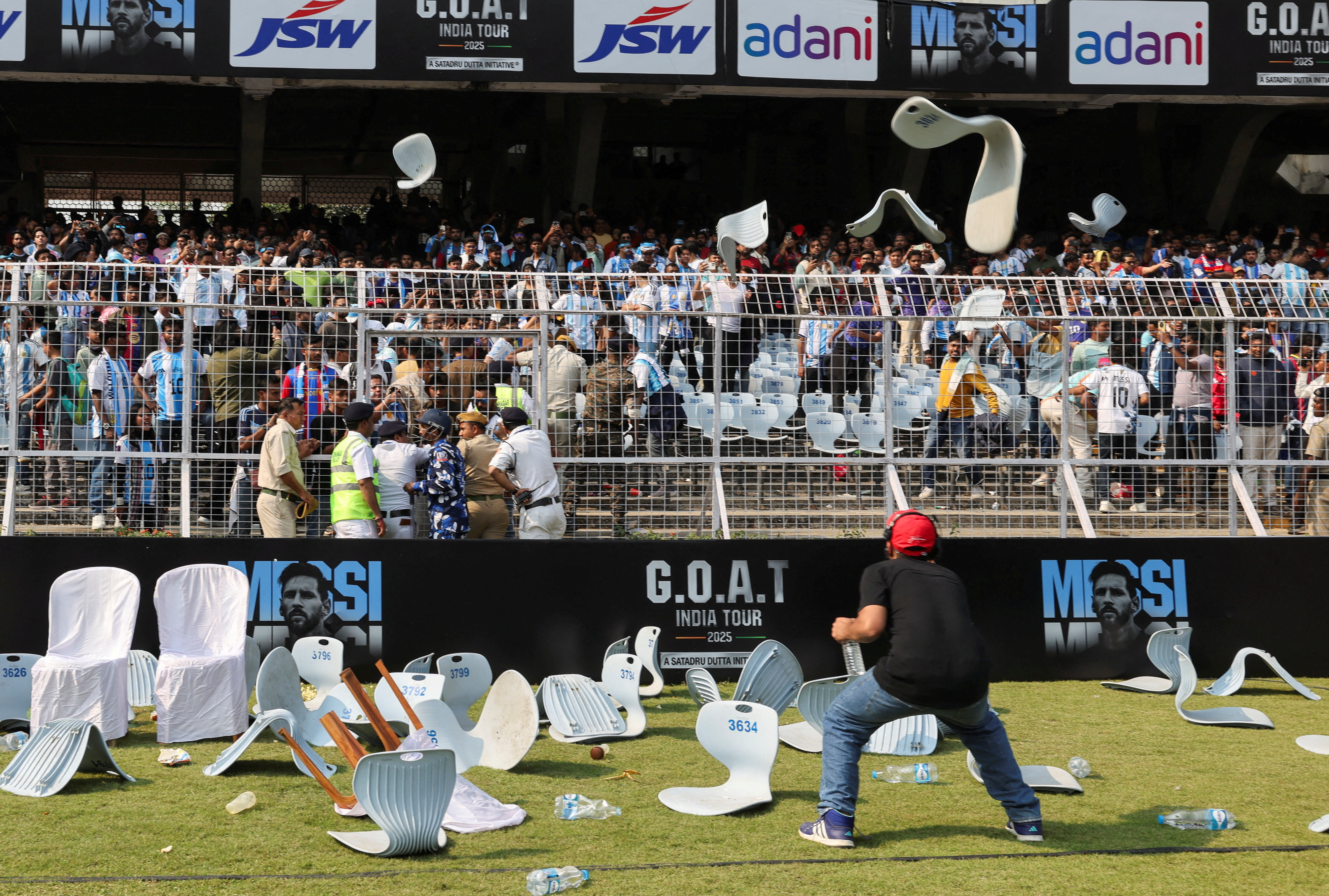 A man ducks to protect himself as fans throw chairs after Argentine soccer star Lionel Messi leaves the Vivekananda Yuva Bharati Krirangan stadium during his India tour, in Kolkata, India, December 13, 2025. REUTERS/Sahiba Chawdhary      TPX IMAGES OF THE
