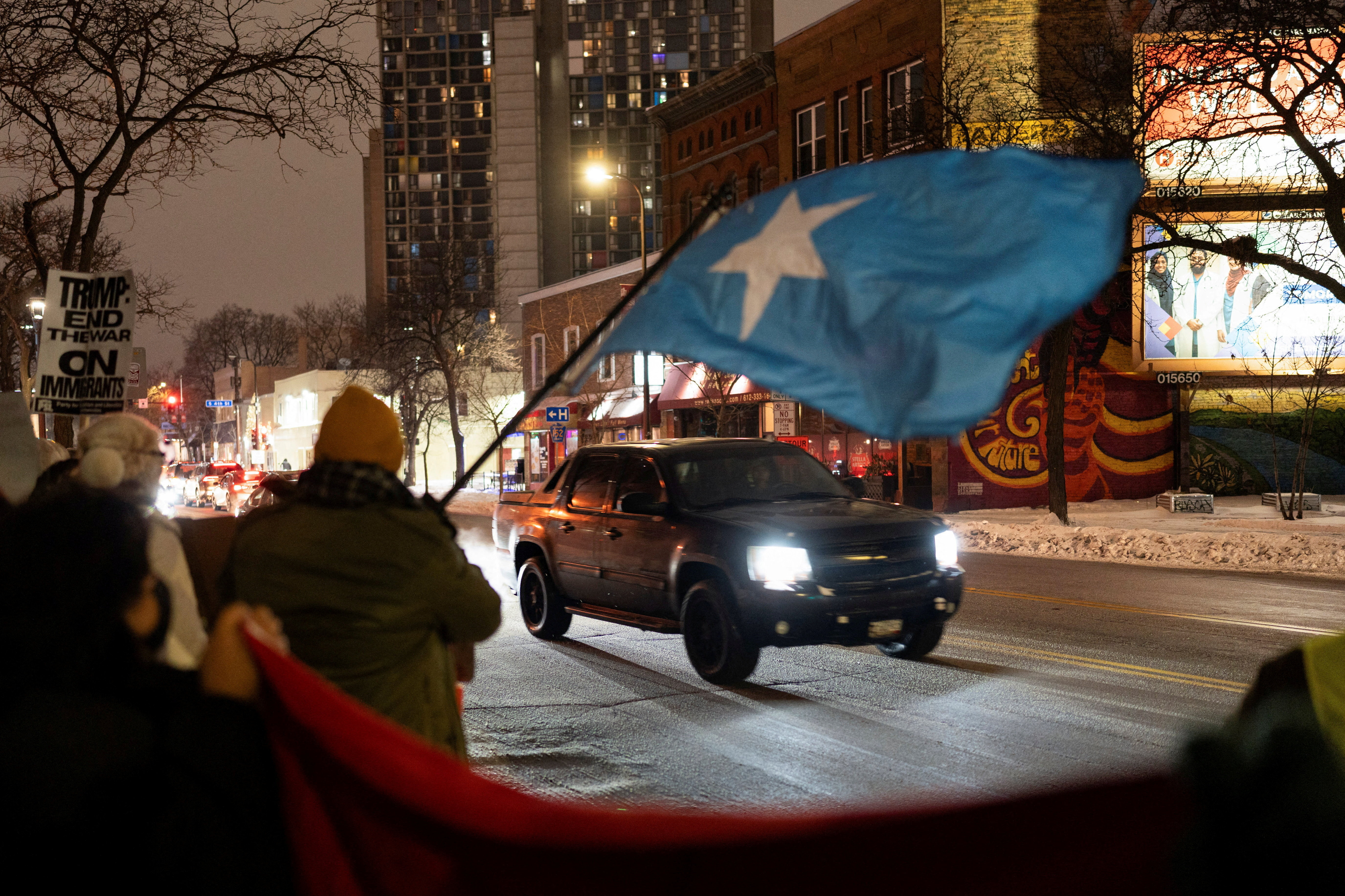 A demonstrator waves a flag of Somalia as a vehicle passes by a rally in protest against Immigration and Customs Enforcement (ICE)