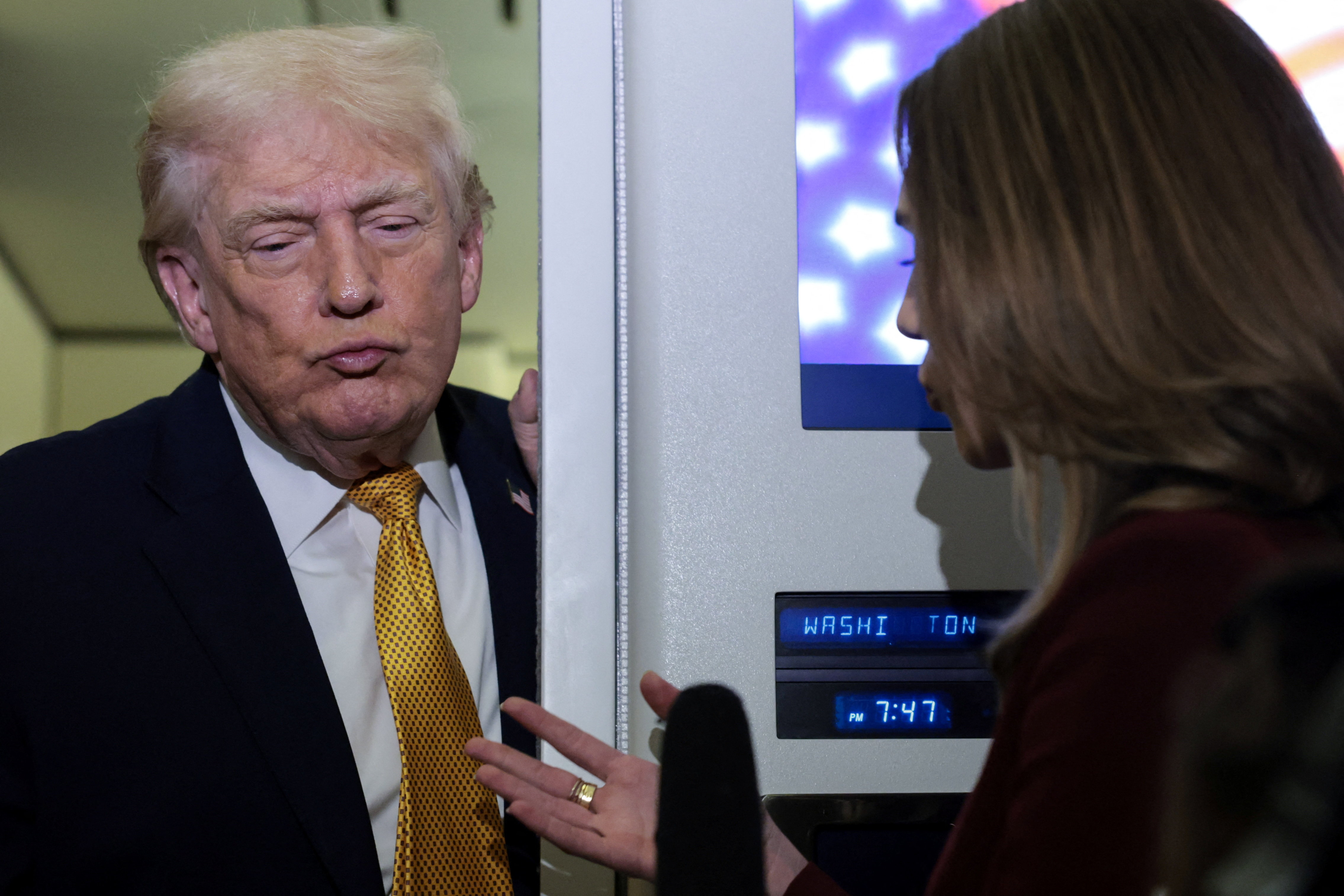 U.S. President Donald Trump listens to a reporter’s question aboard