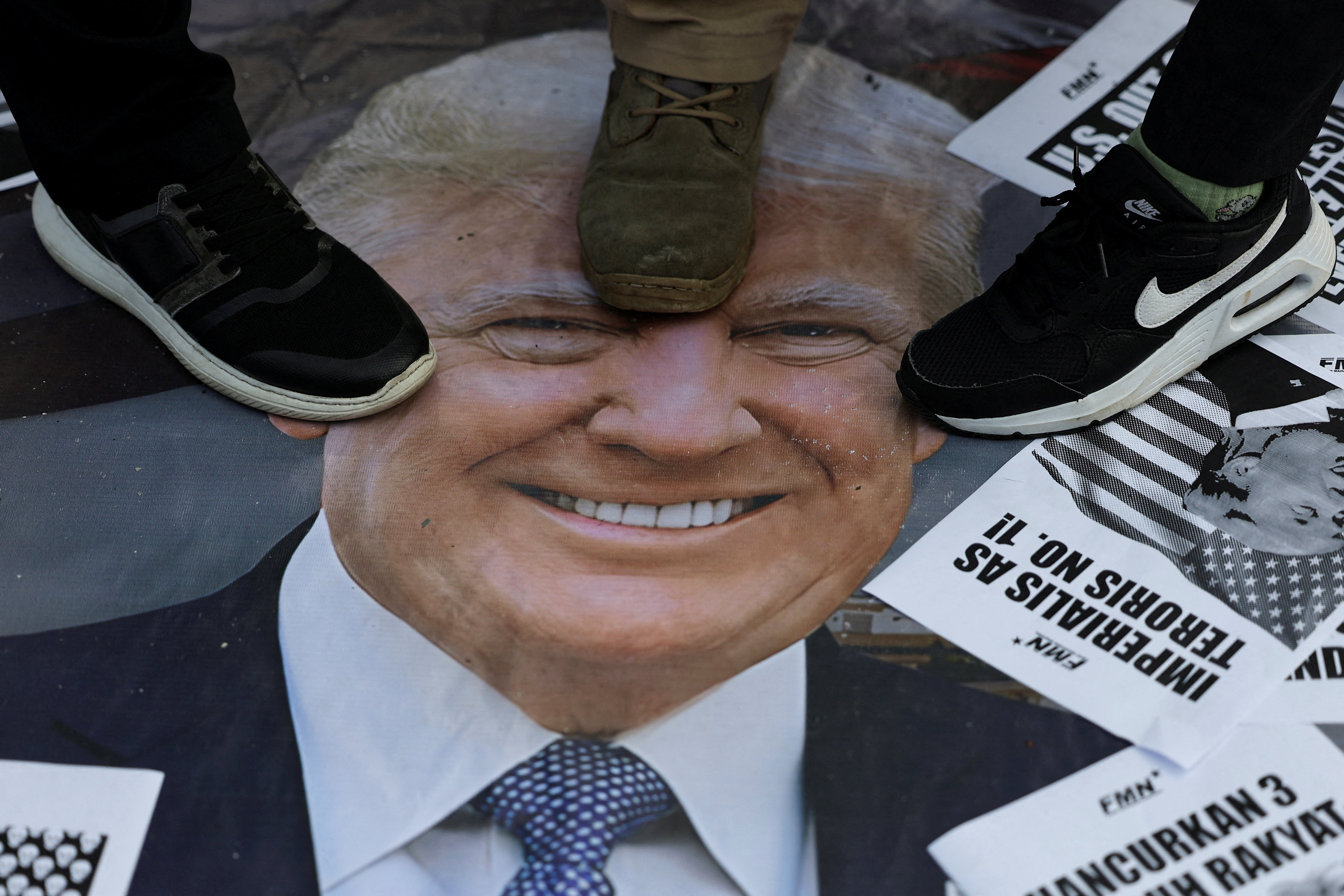 Activists step on a poster with the image of U.S. President Donald Trump