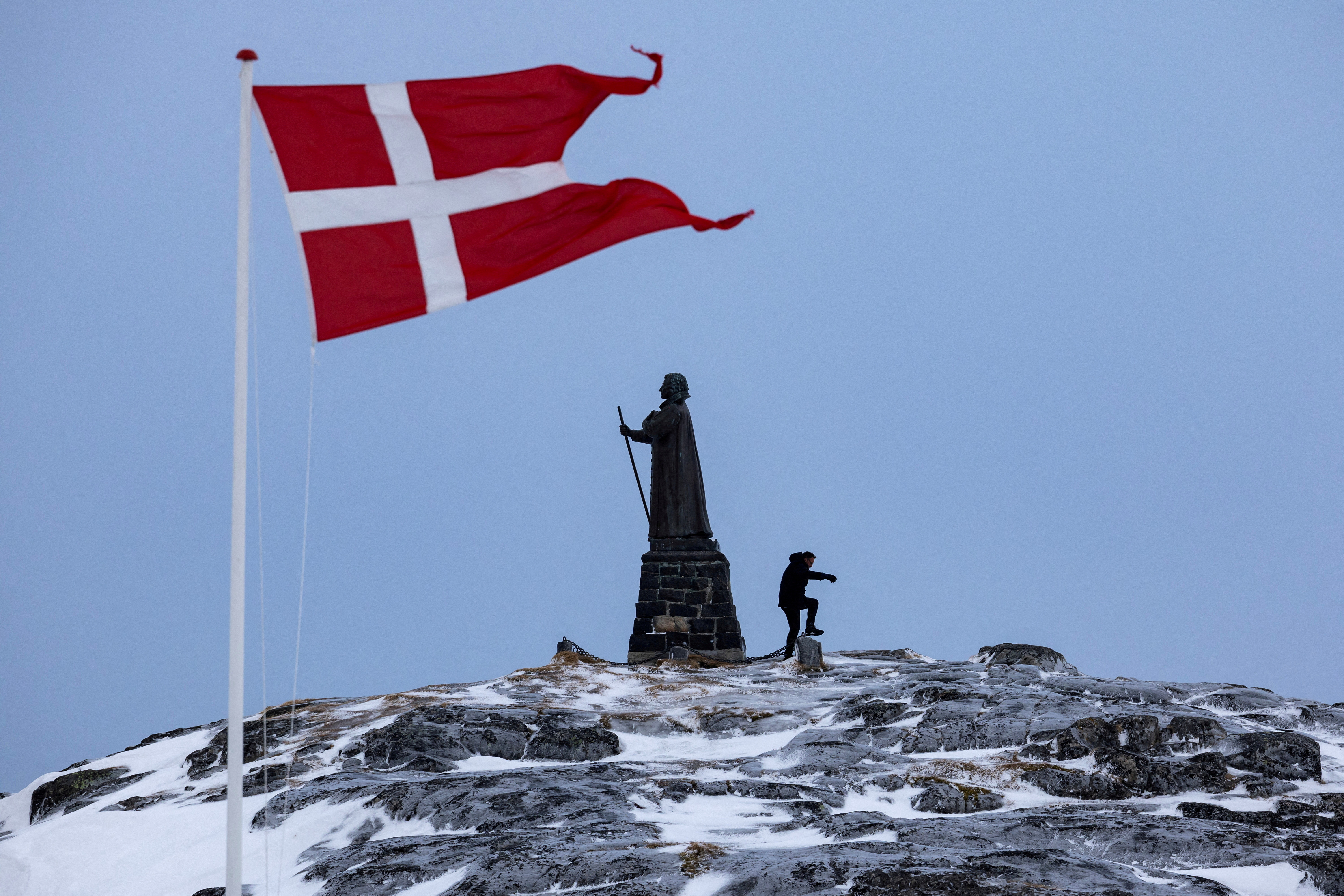 FILE PHOTO: A man walks as Danish flag flutters next to Hans Egede Statue ahead of a March 11 general election in Nuuk, Greenland, March 9, 2025. REUTERS/Marko Djurica/File Photo