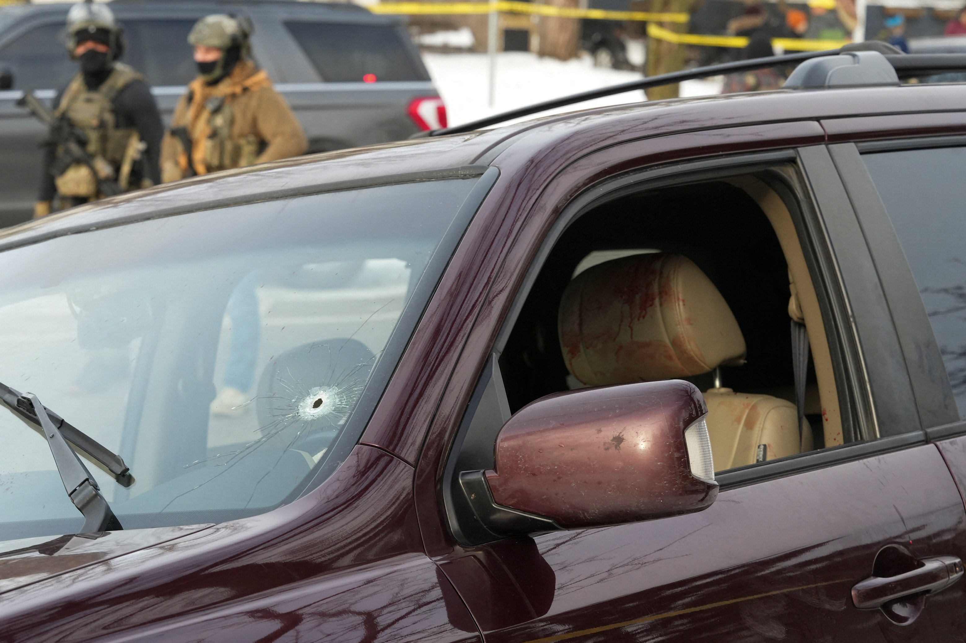 Federal agents gather near a vehicle with a bullet hole the windshield after its driver was shot by a U.S. immigration agent, according to local and federal officials, in Minneapolis, Minnesota, U.S., January 7, 2026. REUTERS/Tim Evans