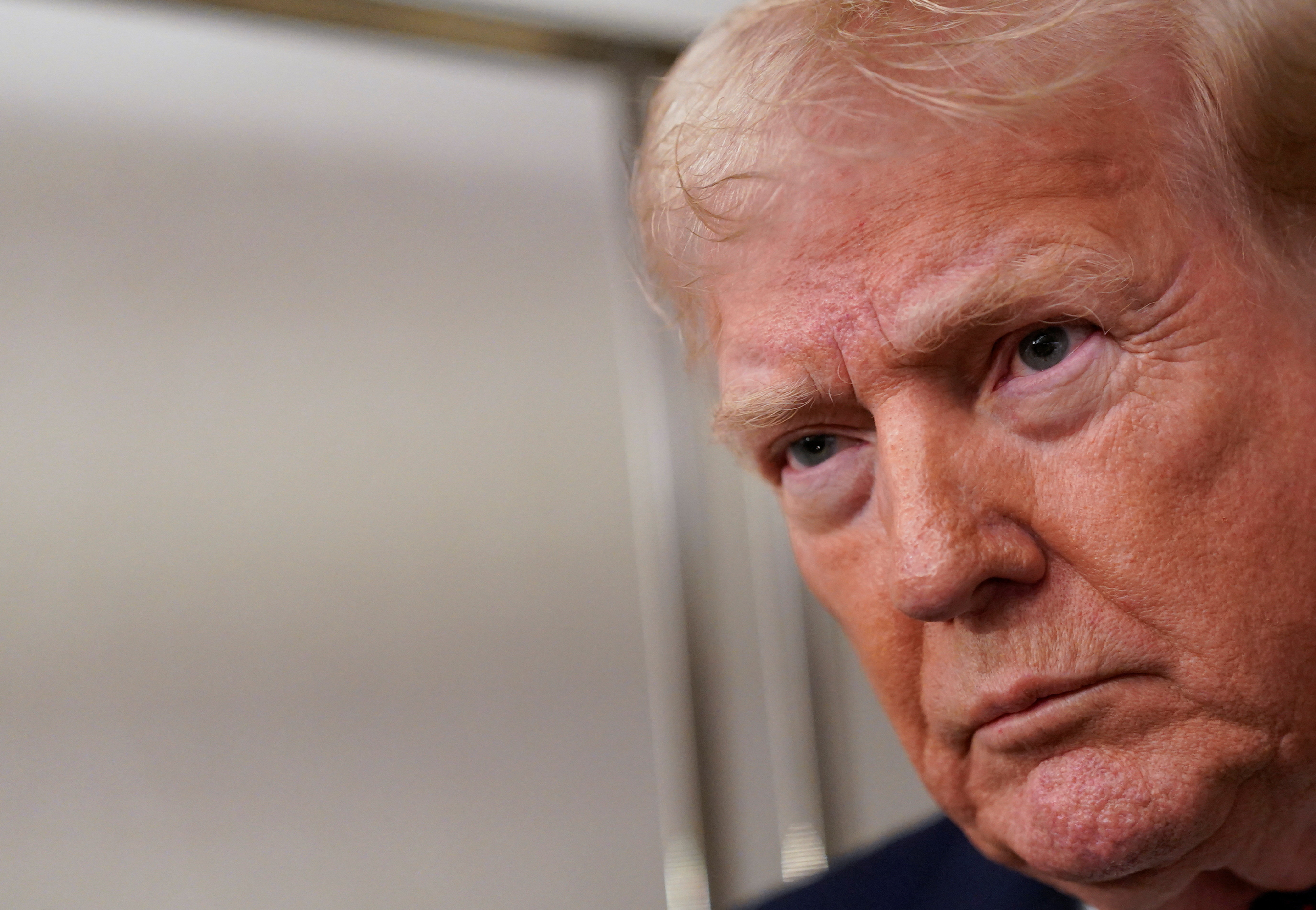 U.S. President Donald Trump looks on as he meets with members of the media aboard Air Force One