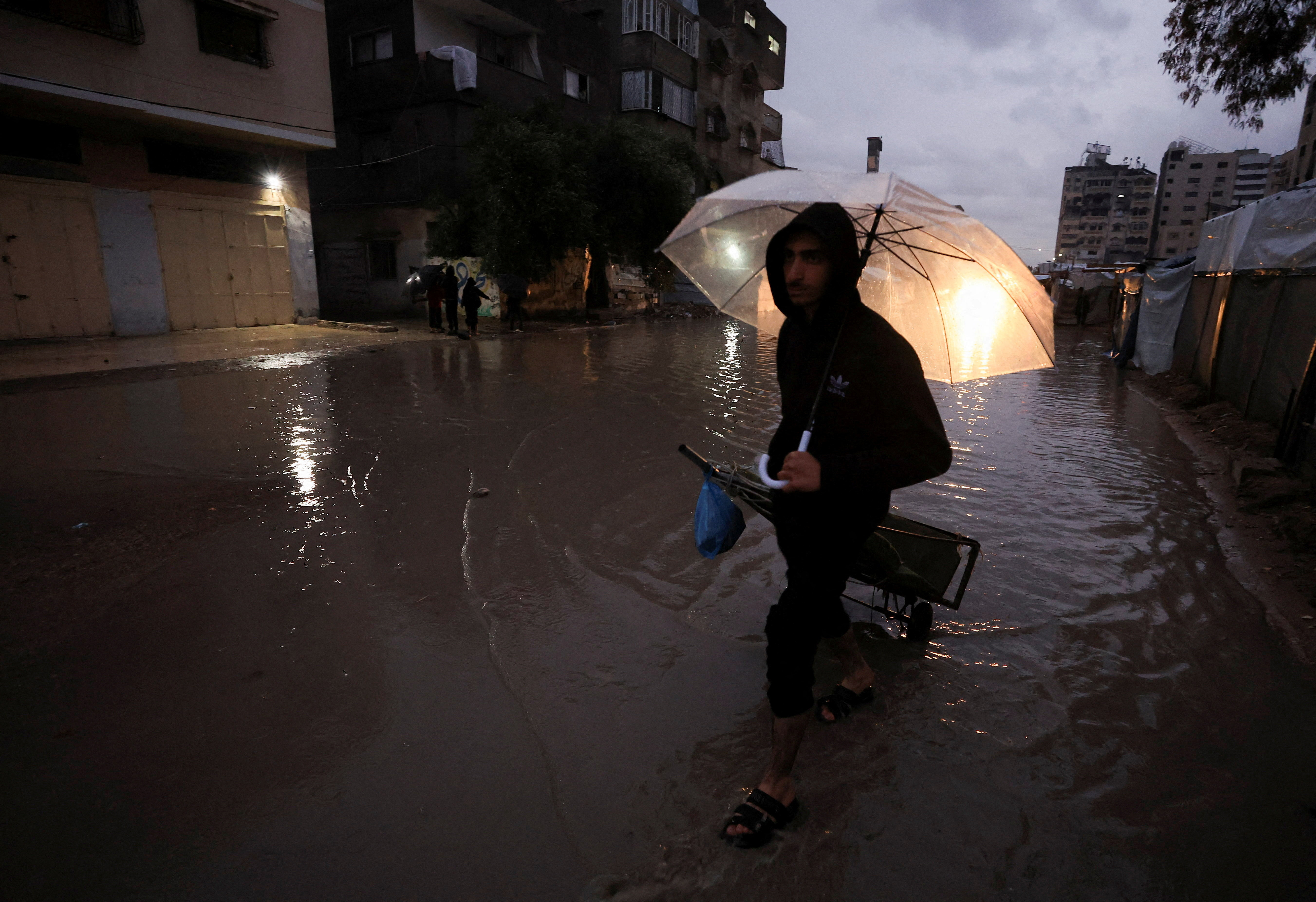 A displaced Palestinian walks through a flooded street on