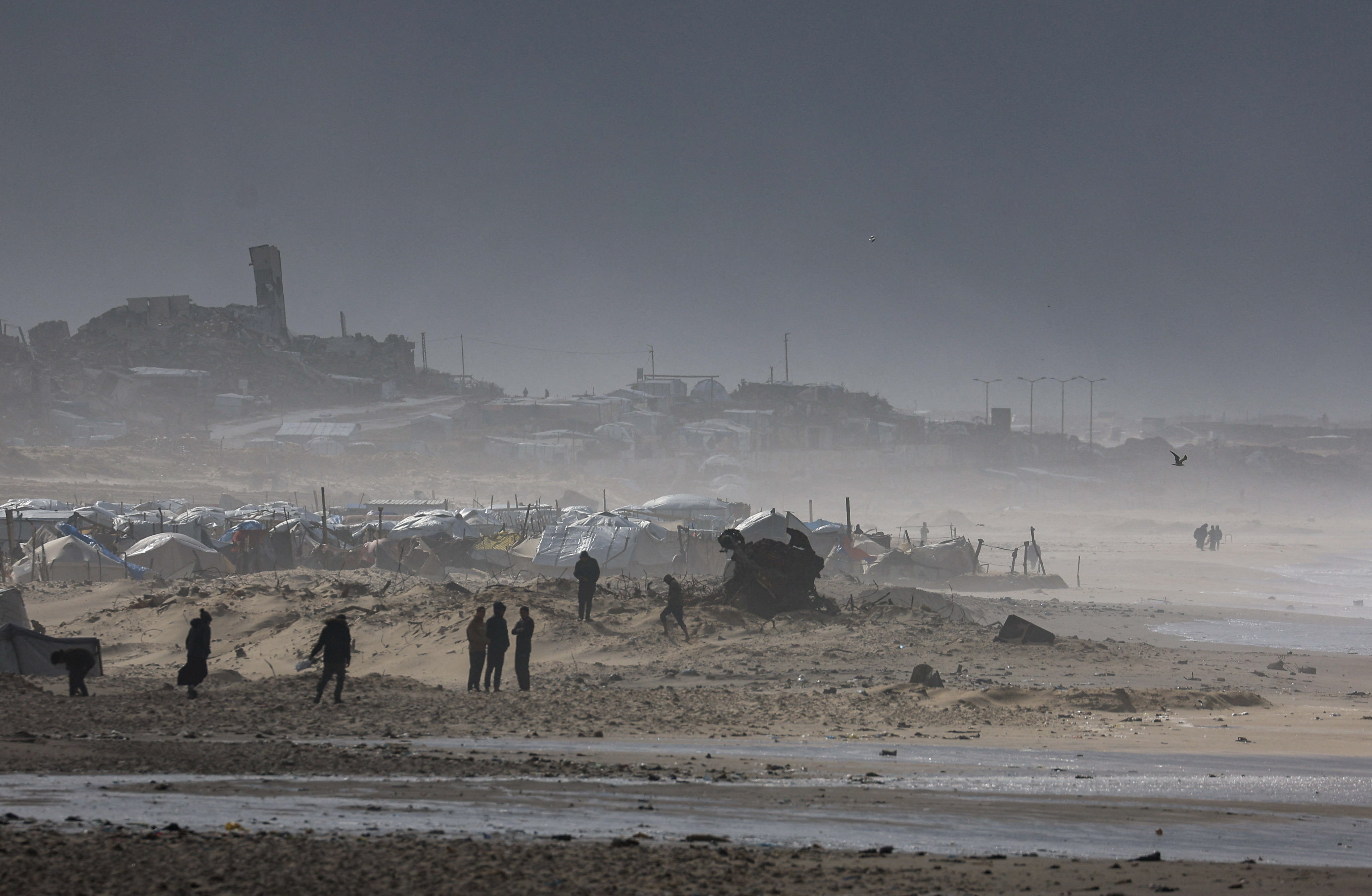 Palestinians gather near tents sheltering displaced people, amid a windstorm, in Gaza City, January 13, 2026. REUTERS/Dawoud Abu Alkas     TPX IMAGES OF THE DAY