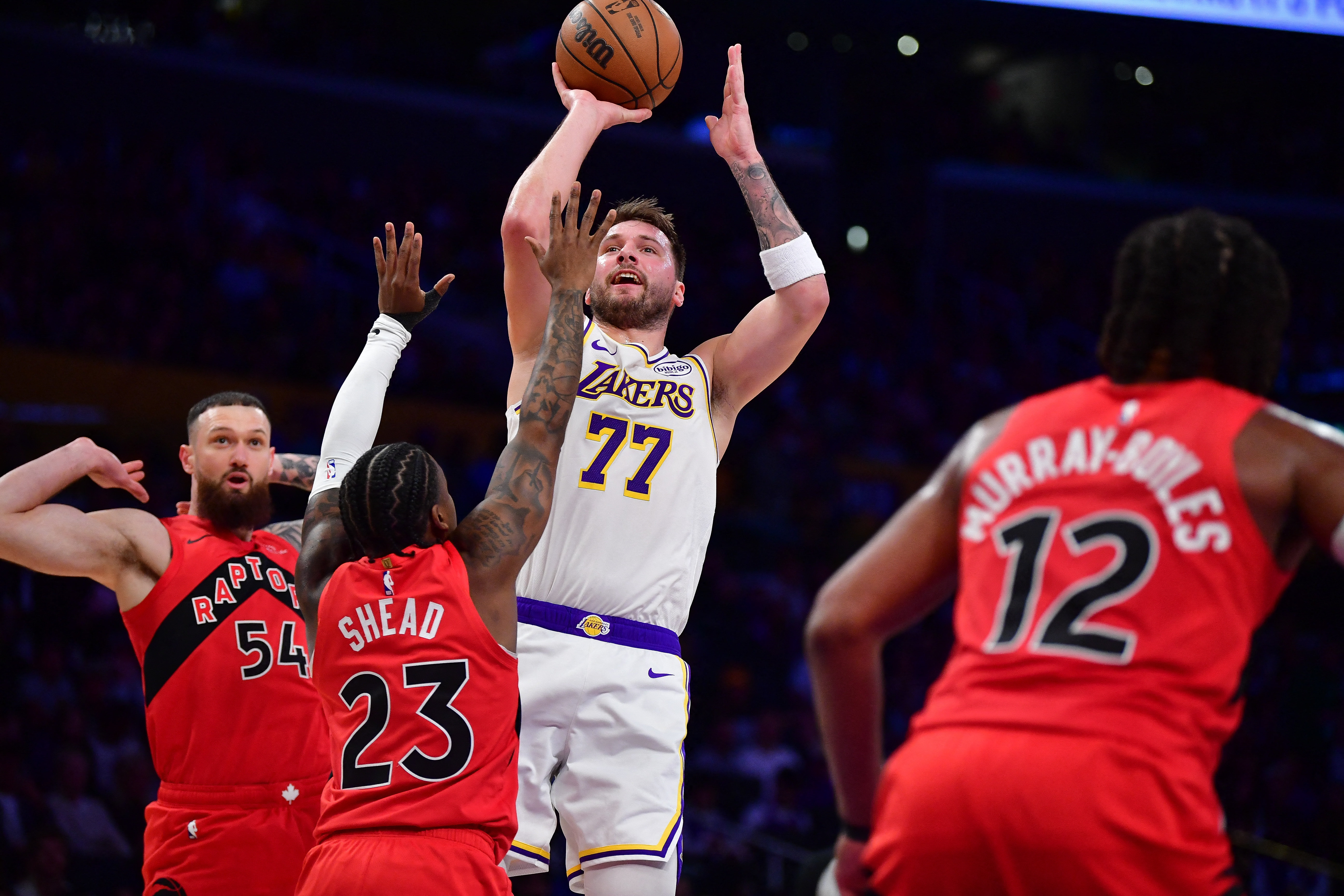 Jan 18, 2026; Los Angeles, California, USA; Los Angeles Lakers guard Luka Doncic (77) shoots against Toronto Raptors guard Jamal Shead (23) during the first half at Crypto.com Arena. Mandatory Credit: Gary A. Vasquez-Imagn Images