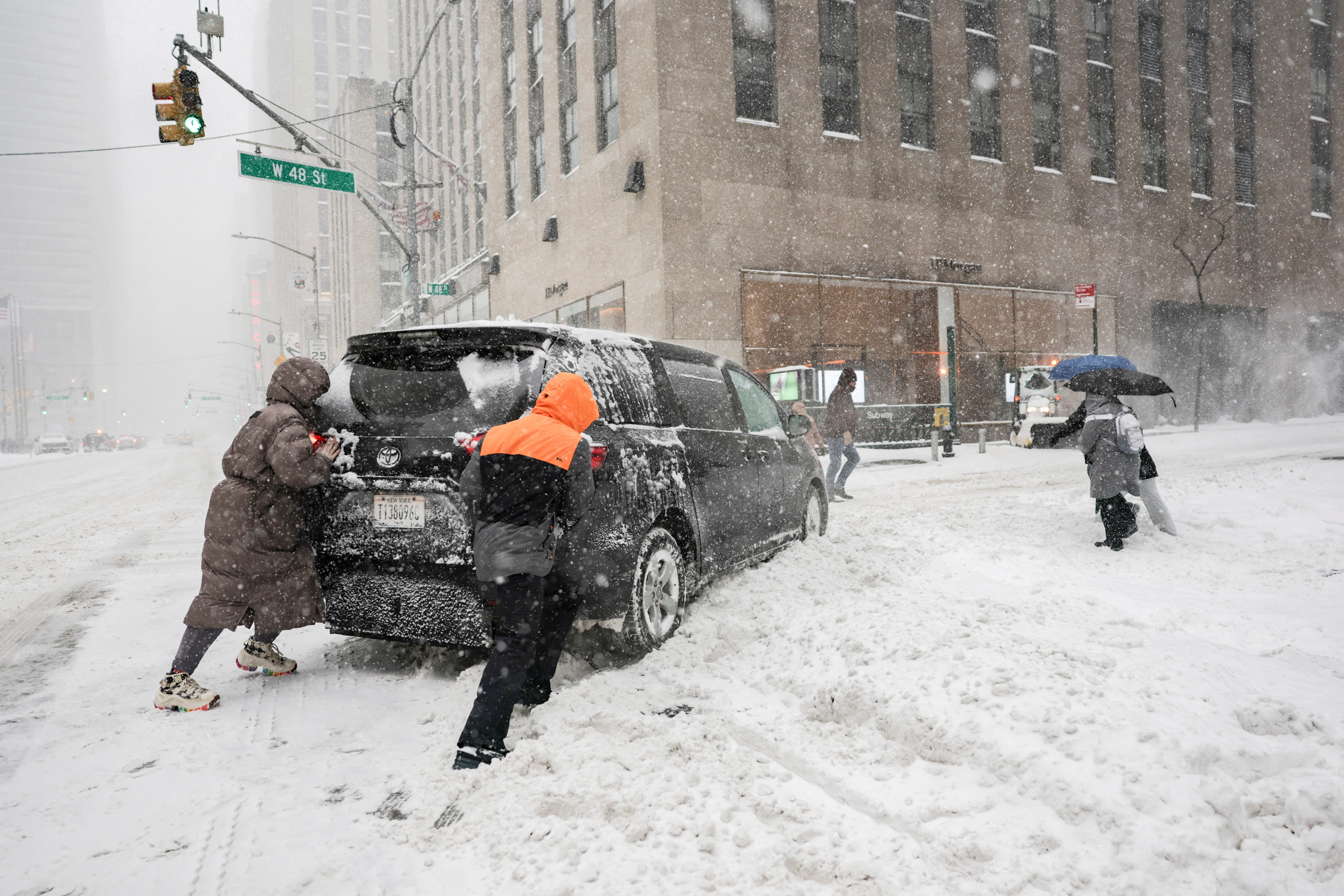 People help by pushing a vehicle near Times Square as a major winter