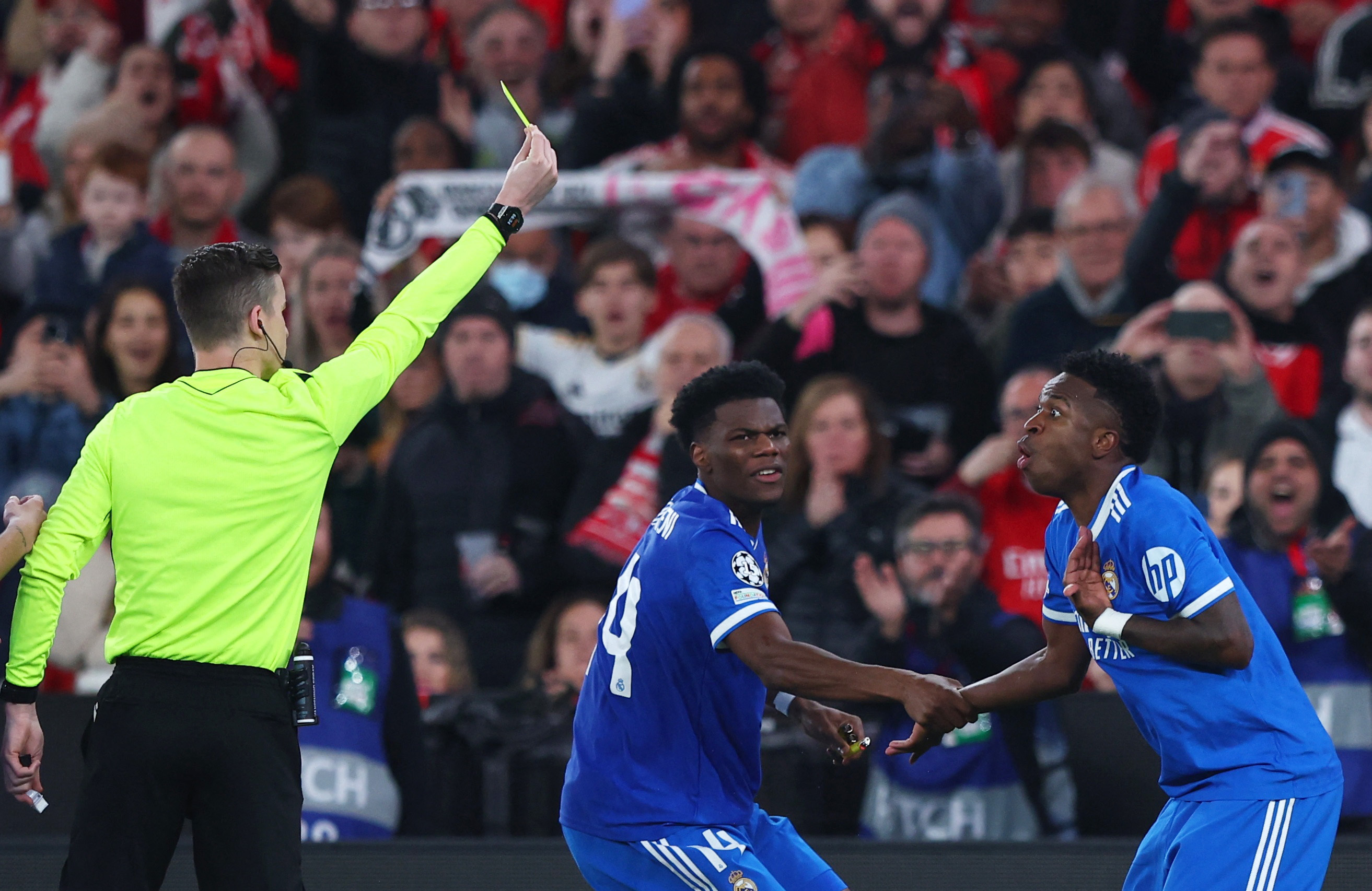 Soccer Football - UEFA Champions League - Play Off - First Leg - Benfica v Real Madrid - Estadio da Luz, Lisbon, Portugal - February 17, 2026 Real Madrid's Vinicius Junior is shown a yellow card by referee Francois Letexier as Aurelien Tchouameni reacts R