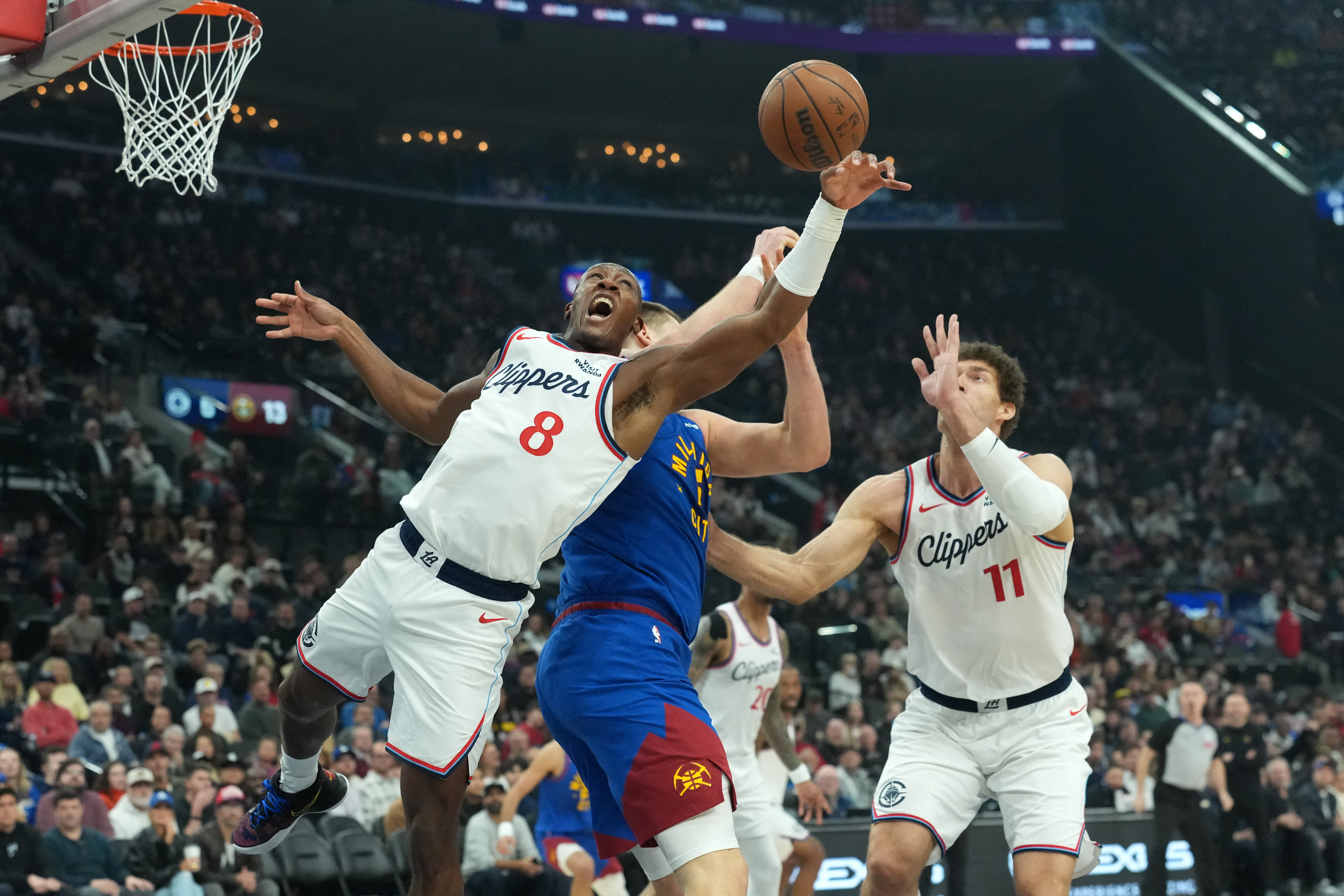 Feb 19, 2026; Inglewood, California, USA; LA Clippers guard Kris Dunn (8) and center Brook Lopez (11) battle for the ball with Denver Nuggets center Nikola Jokic (15) in the first half at Intuit Dome. Mandatory Credit: Kirby Lee-Imagn Images