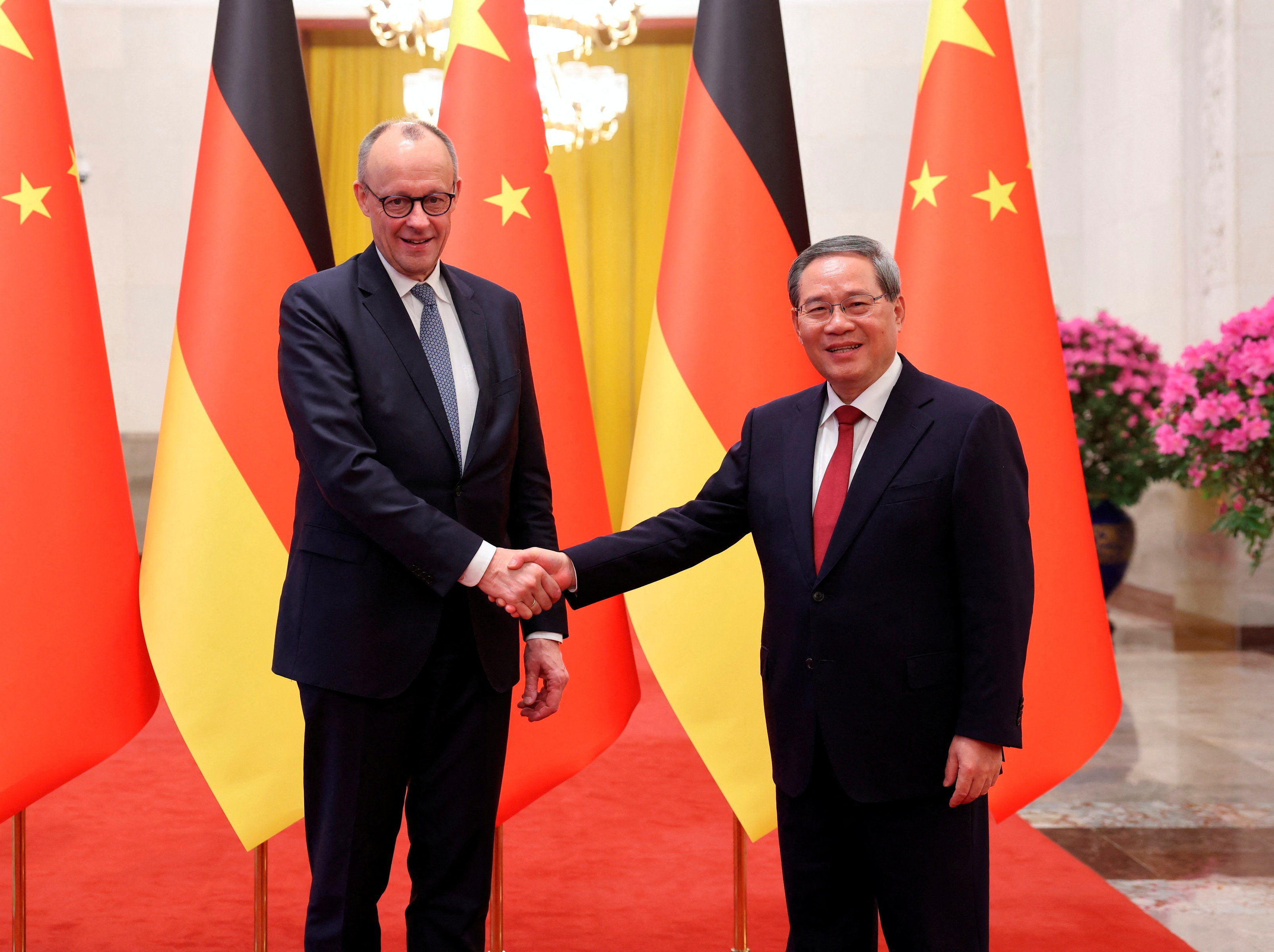 China's Premier Li Qiang and Germany's Chancellor Friedrich Merz shake hands at the Great Hall of the People in Beijing, China