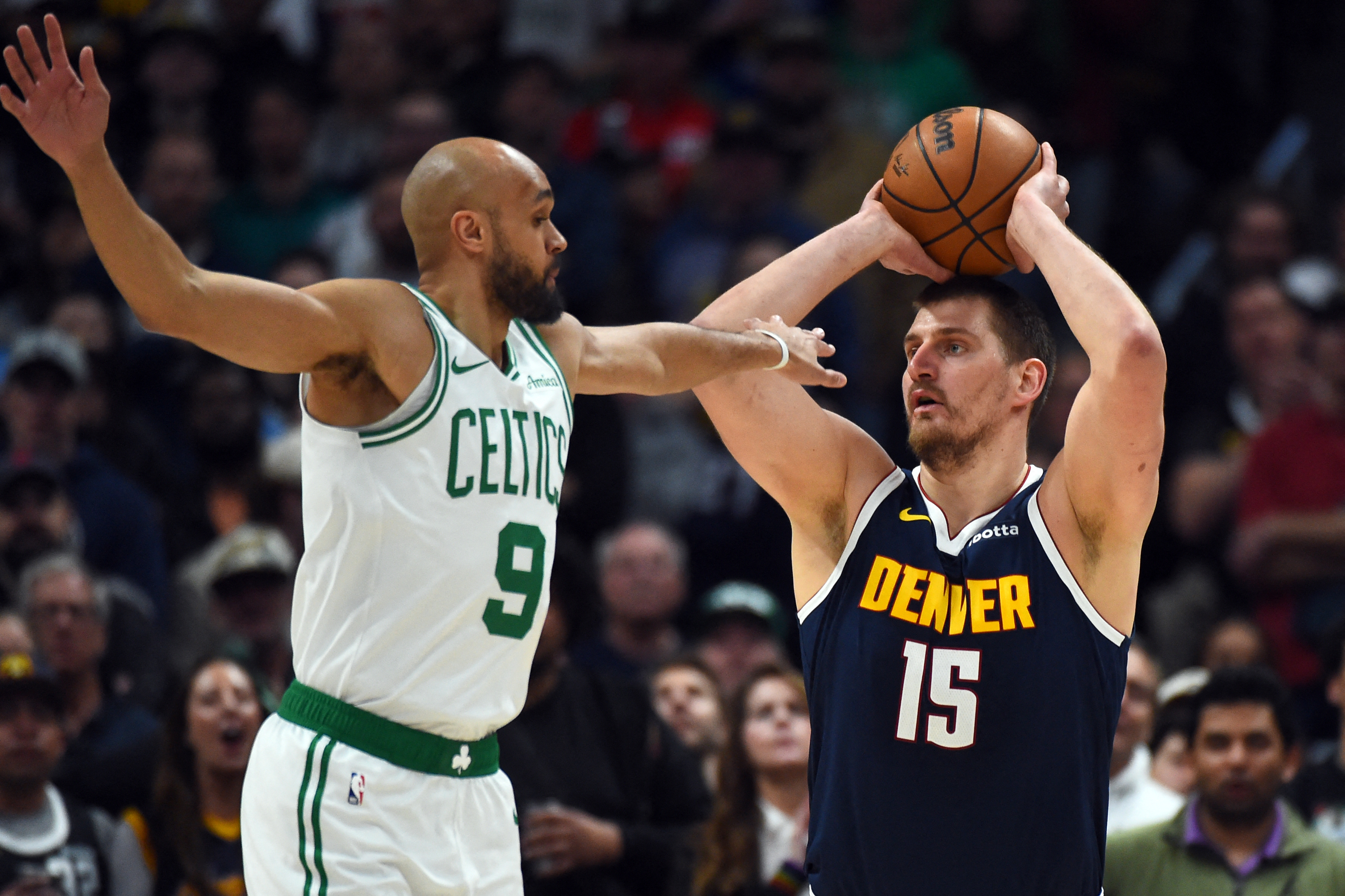 Feb 25, 2026; Denver, Colorado, USA; Denver Nuggets center Nikola Jokic (15) looks to pass the ball as he is defended by Boston Celtics guard Derrick White (9) during the first half at Ball Arena. Mandatory Credit: Christopher Hanewinckel-Imagn Images