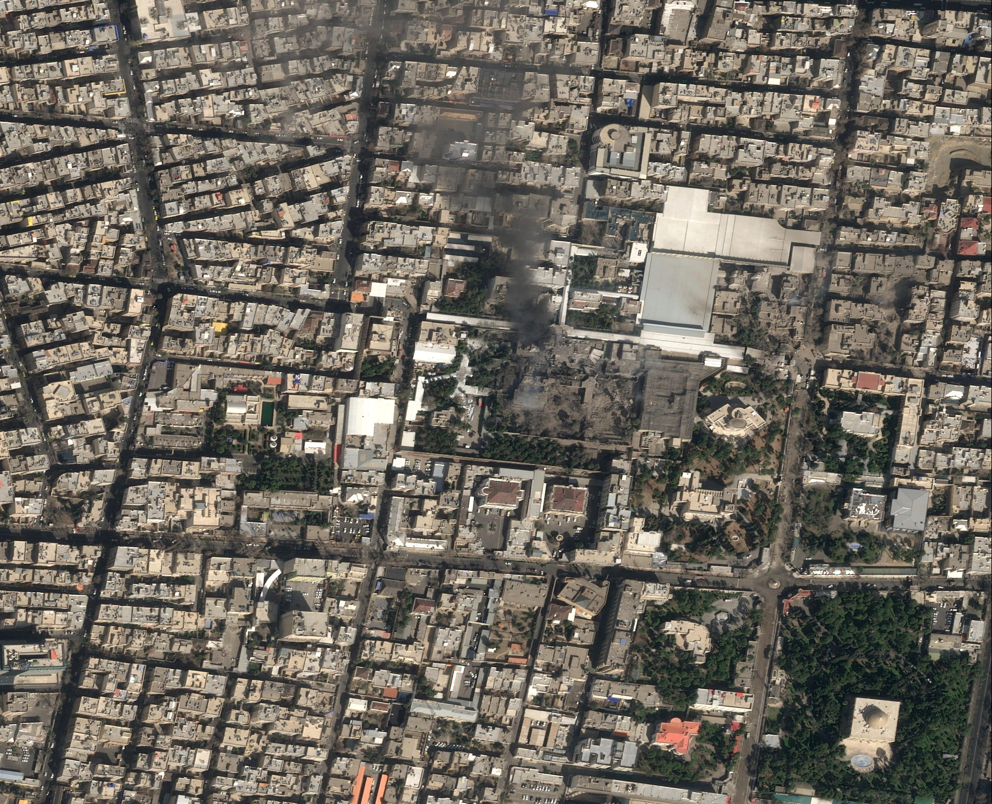 A satellite image shows black smoke rising and heavy damage at Iranian