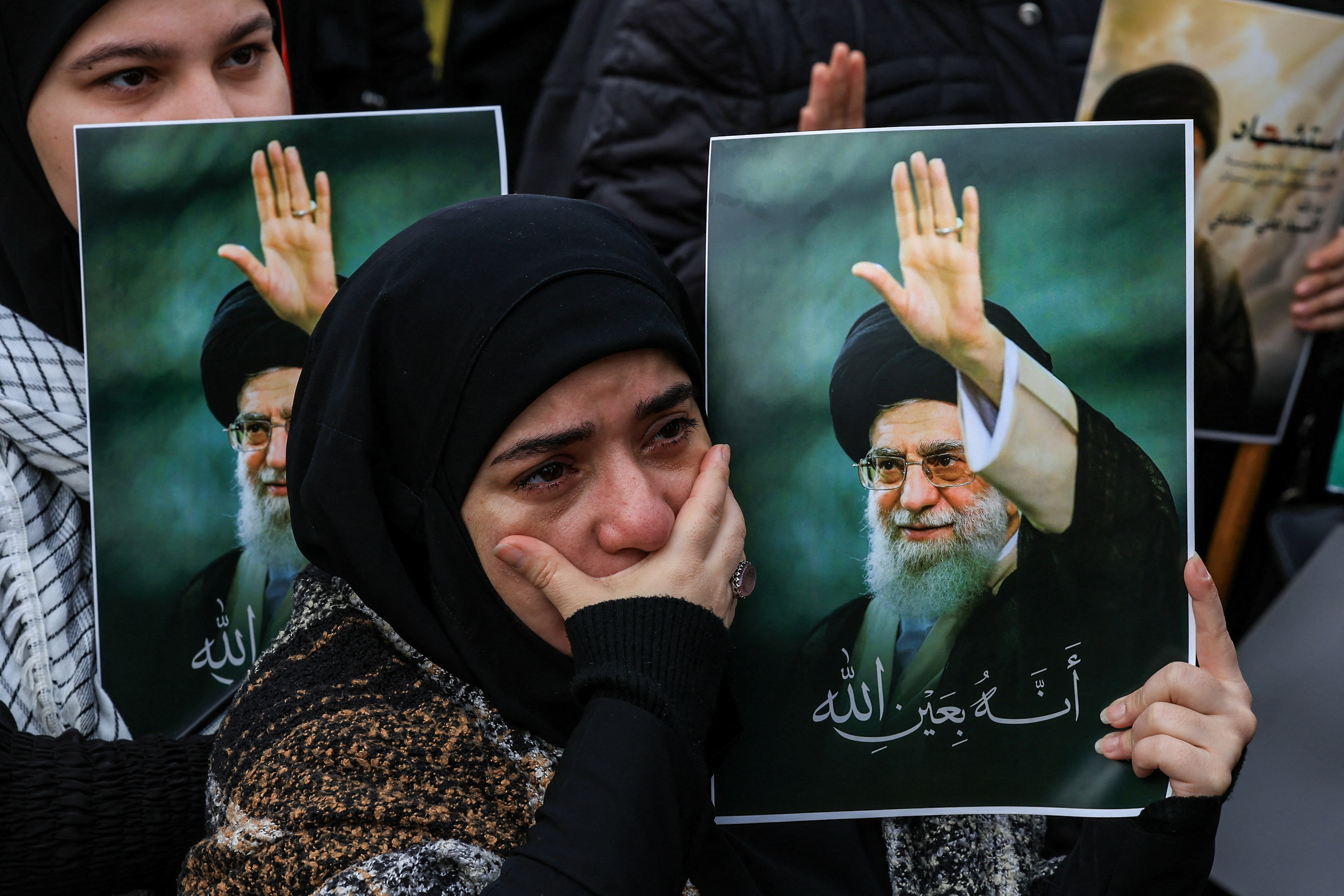A woman reacts as she holds a placard with an image of Iranian late Supreme