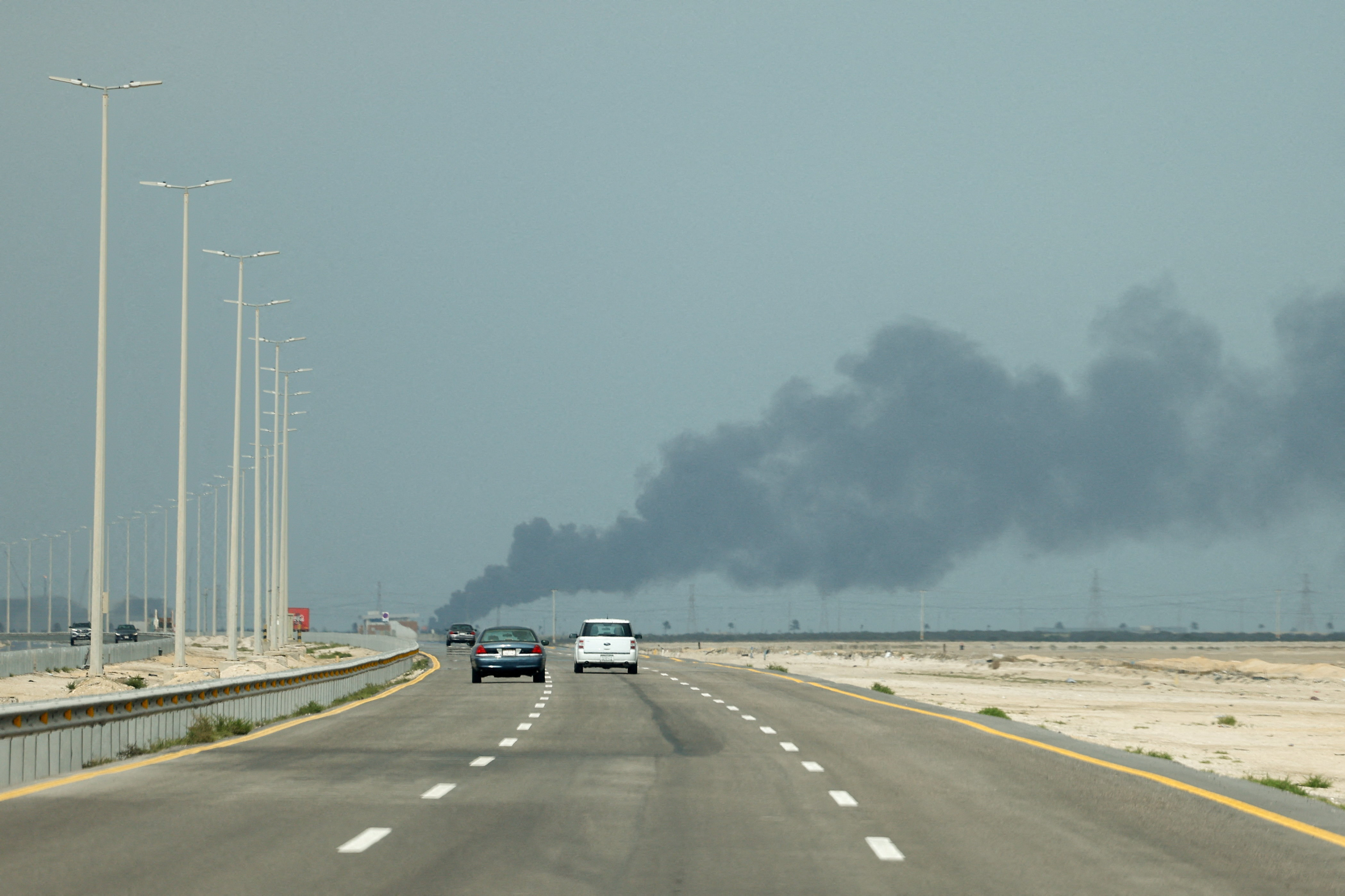 Vehicles move along a road as smoke billows from Saudi Aramco's Ras Tanura oil refinery after a reported Iranian drone strike, amid the U.S.-Israel conflict with Iran, in Ras Tanura, Saudi Arabia, March 2, 2026. REUTERS/Stringer     TPX IMAGES OF THE DAY