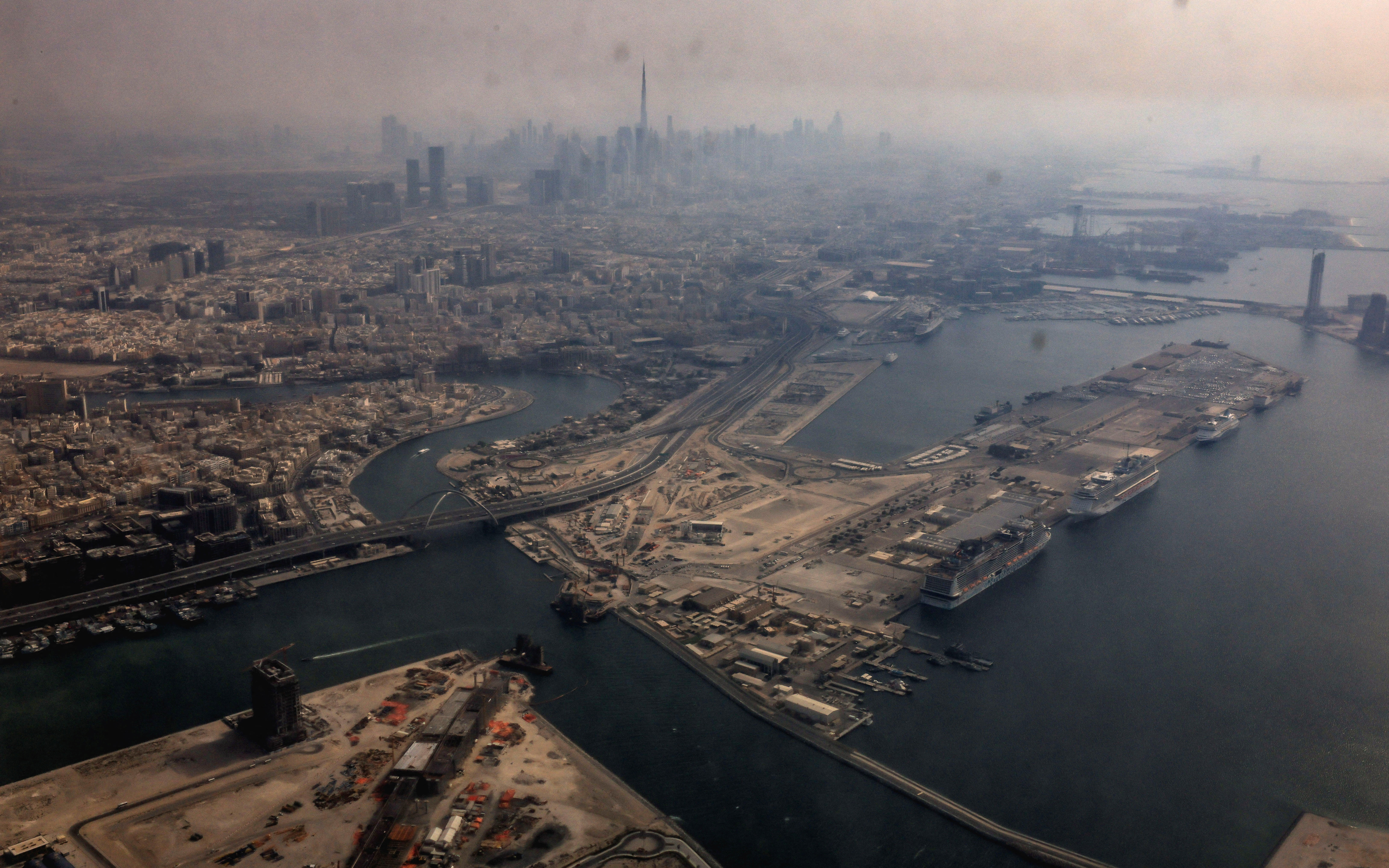 A view from inside a stained window of an airplane shows Dubai