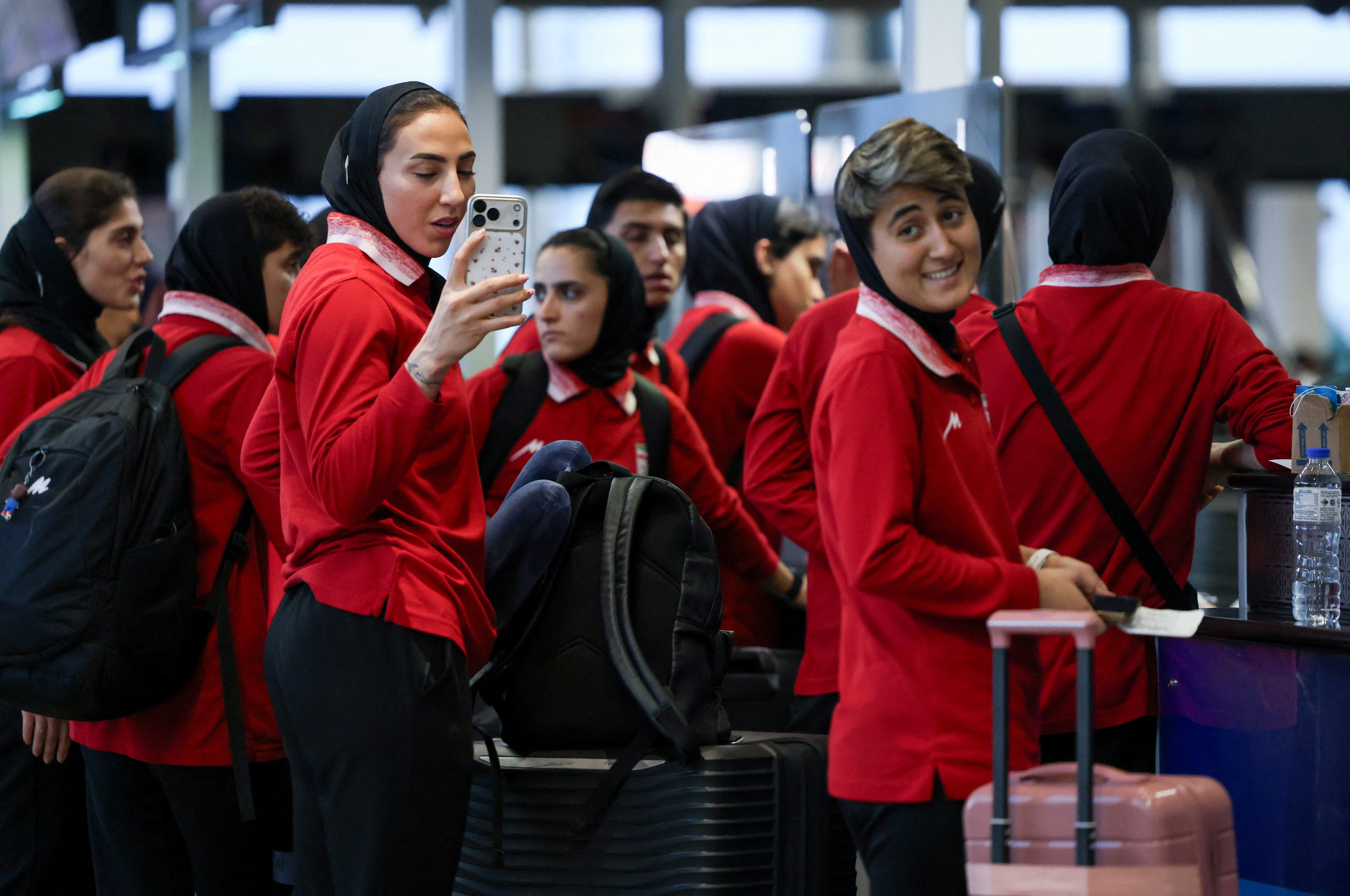 Members of the Iranian women's national soccer team stand at Kuala Lumpur International Airport as they prepare to leave Malaysia after a transit stop on March 11, following a Group A match at the AFC Women's Asian Cup in Australia, while one of their tea