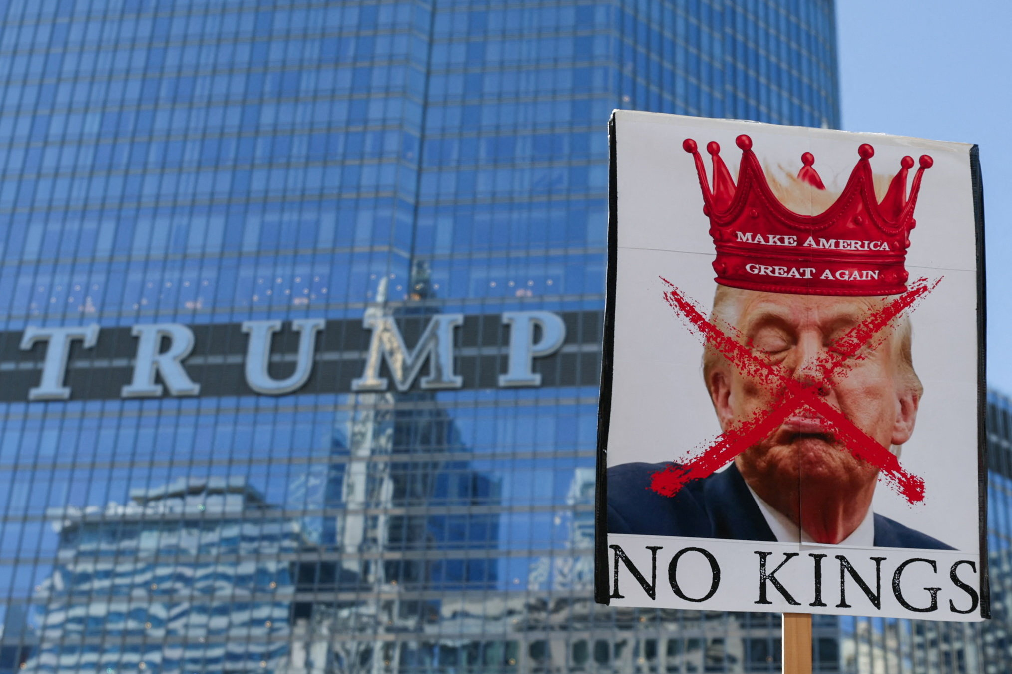 A person holds a sign with an image depicting U.S. President Donald Trump as demonstrators walk past the Trump Tower during a "No Kings" protest