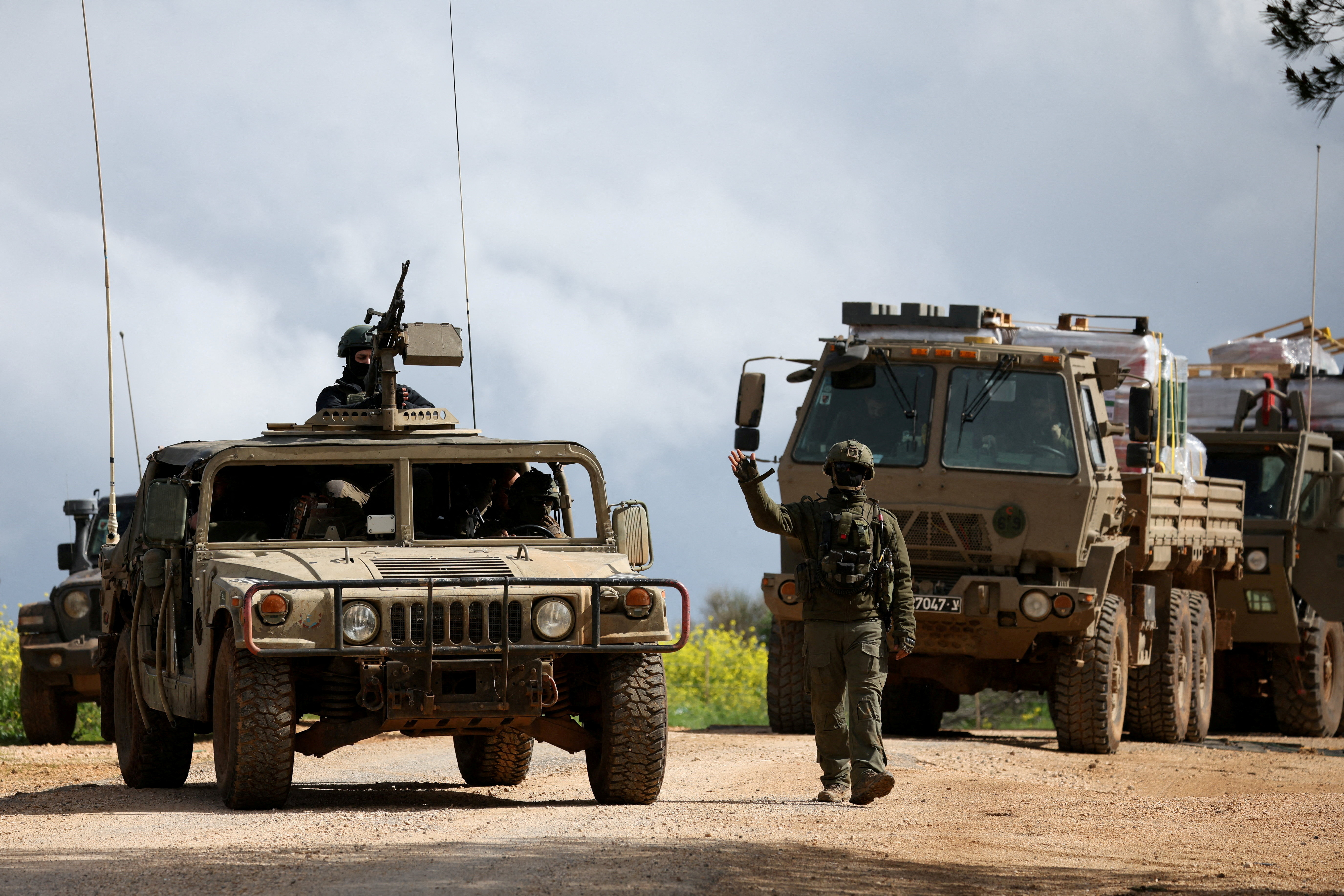 FILE PHOTO: An Israeli soldier gestures while walking next to military vehicles, after Israel forces launched a new campaign against Iran-backed Hezbollah in southern Lebanon