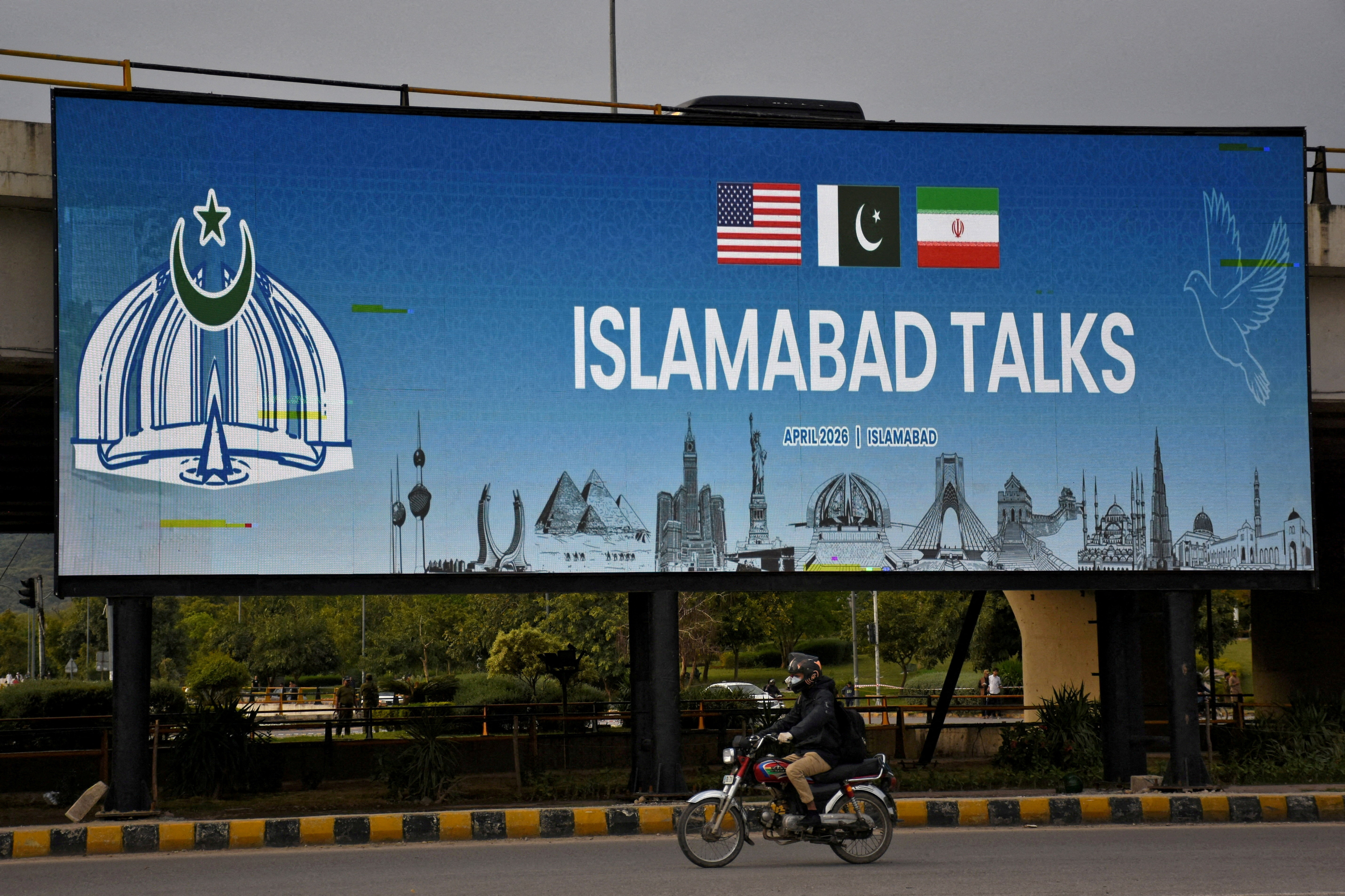 FILE PHOTO: A man rides his motorbike past a billboard installed alongside