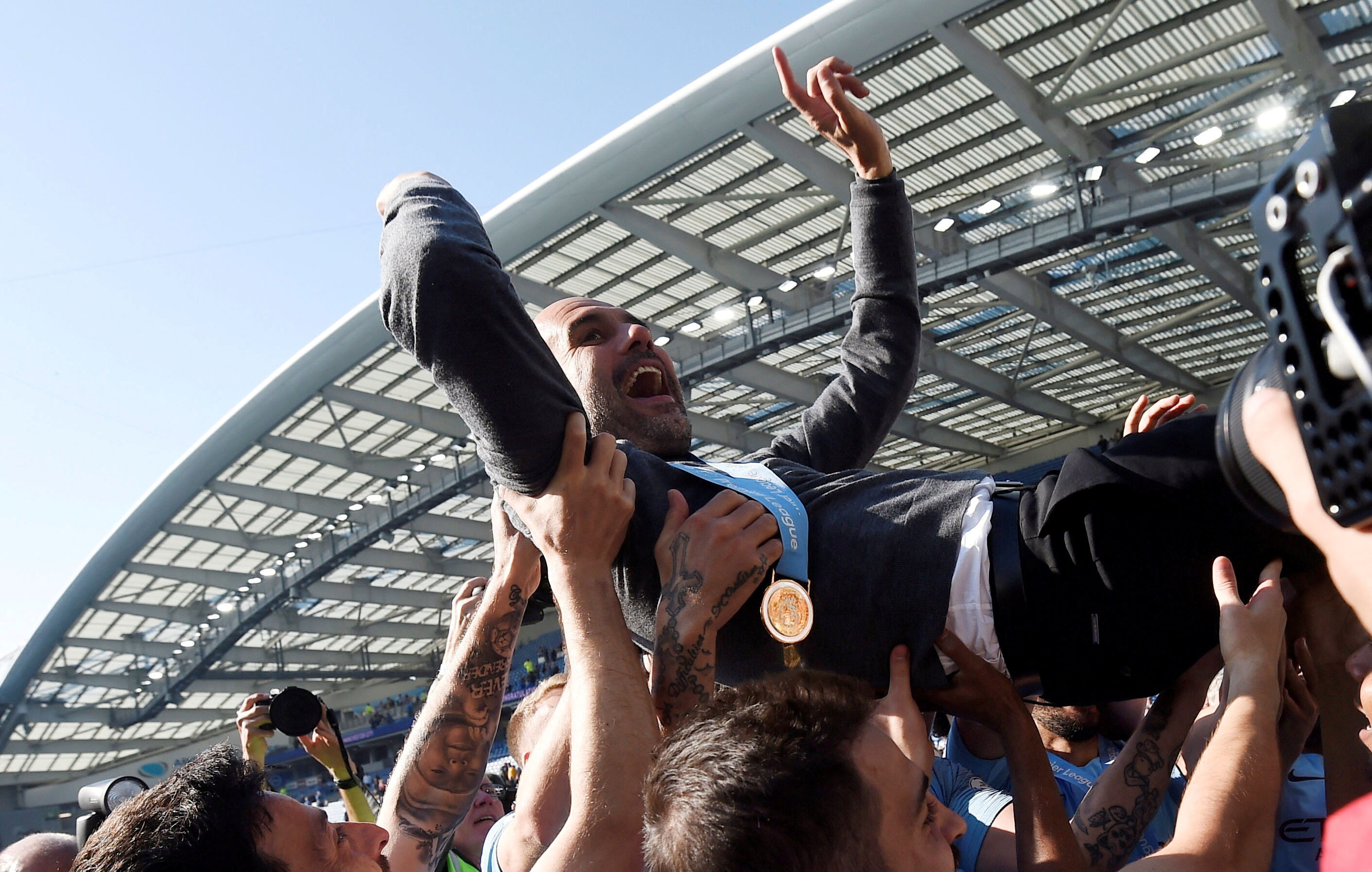 FILE PHOTO: Soccer Football - Premier League - Brighton & Hove Albion v Manchester City - The American Express Community Stadium, Brighton, Britain - May 12, 2019  Manchester City manager Pep Guardiola is thrown in the air by players as they celebrate win