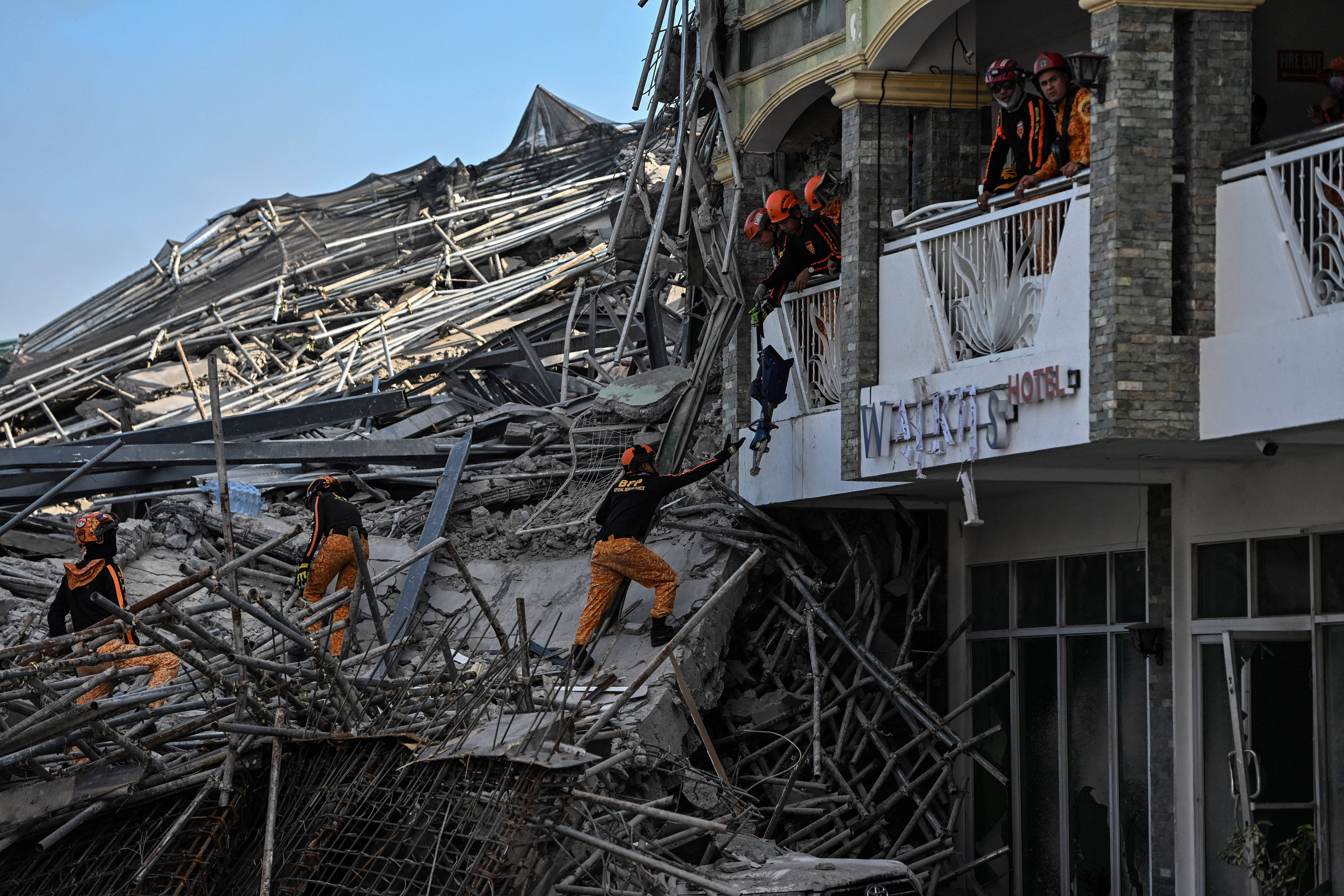 A rescue worker passes equipment to a comrade amidst debris as a nine-story building under construction collapsed in Balibago, Angeles City, Pampanga, Philippines, May 24, 2026. REUTERS/Noel Celis