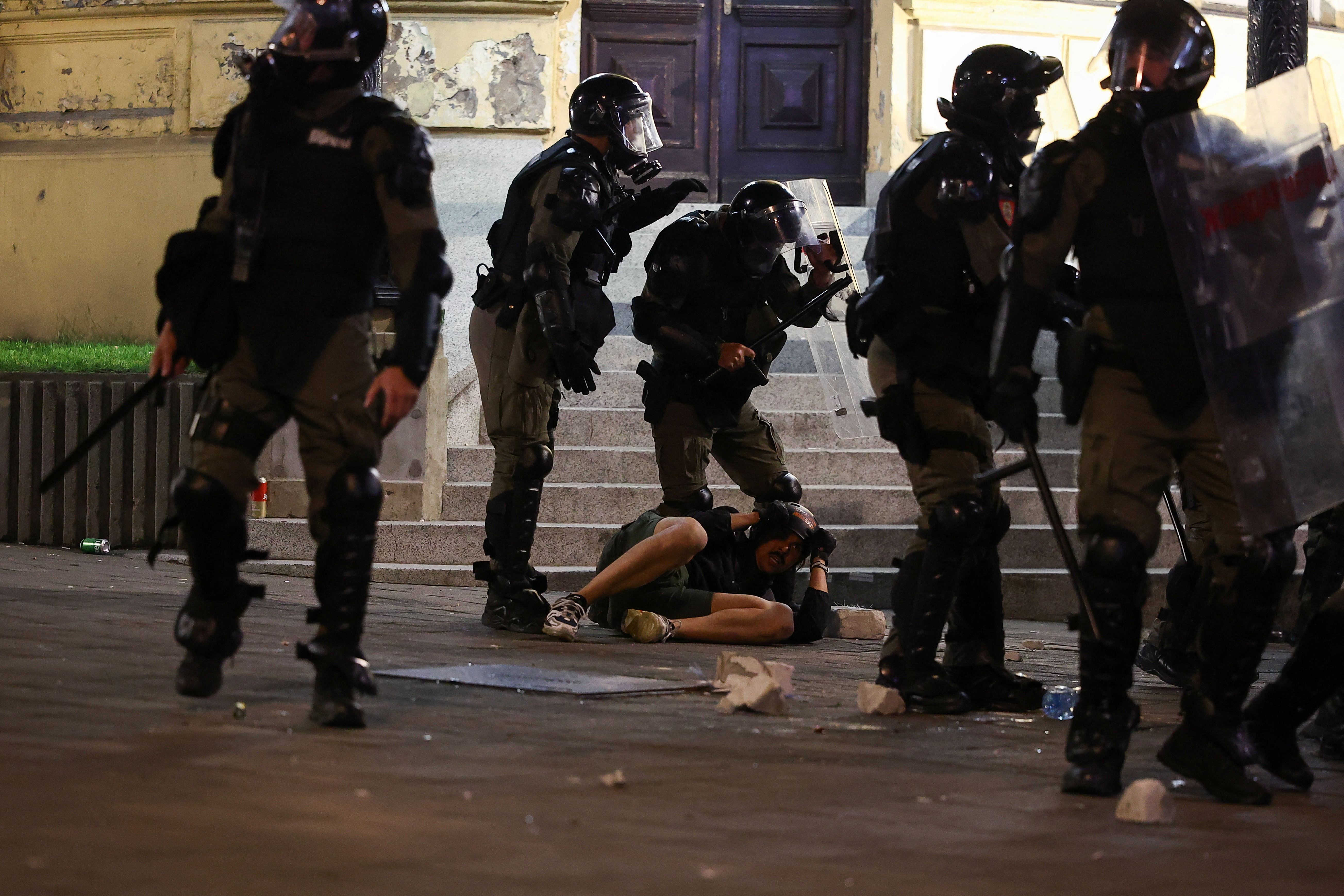 A demonstrator lies on the ground next to members of the Gendarmery