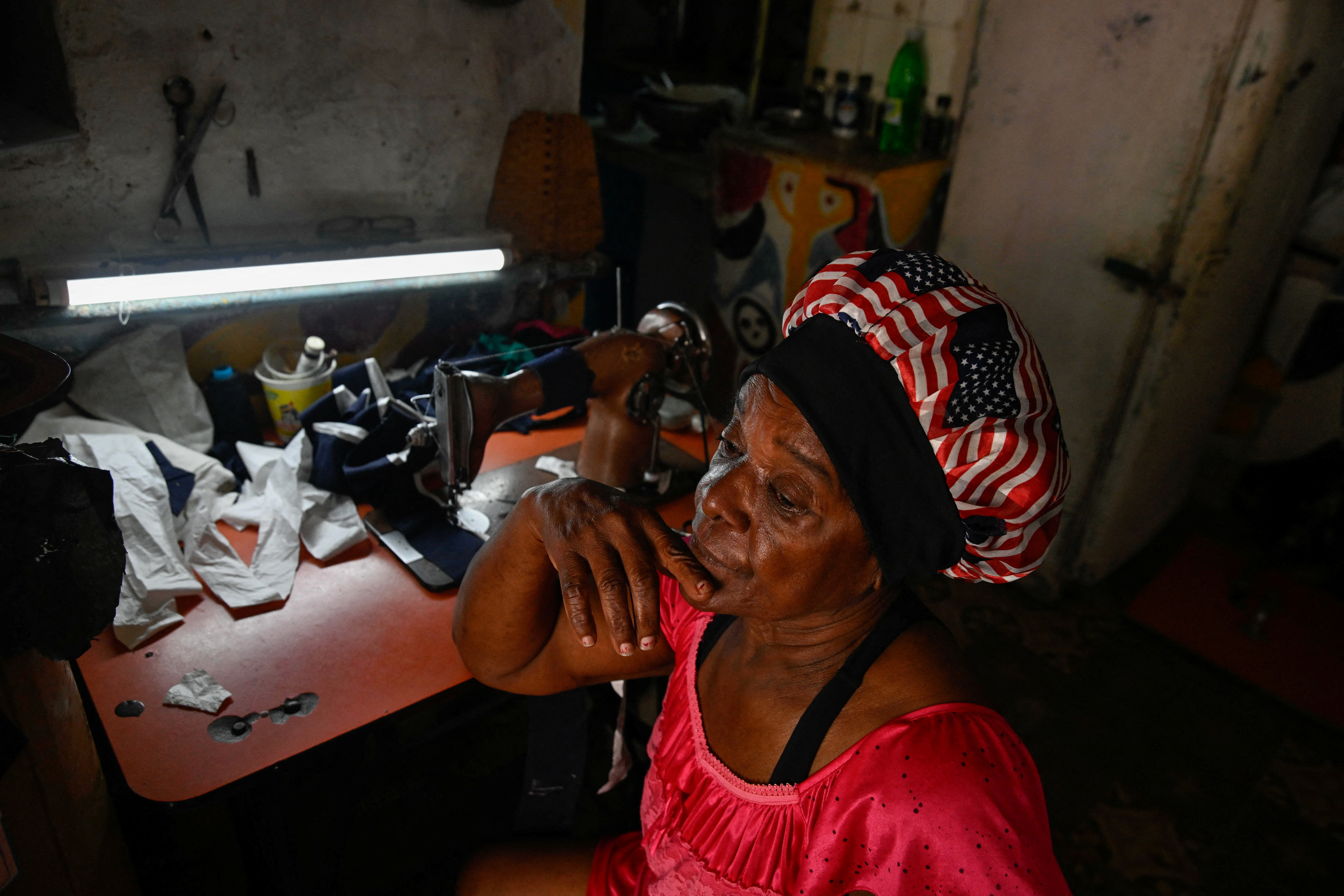 Irma Ribas, 68, who was a pensioner but was rehired at a hospital to work in the sterilization area, sits at her sewing machine at home