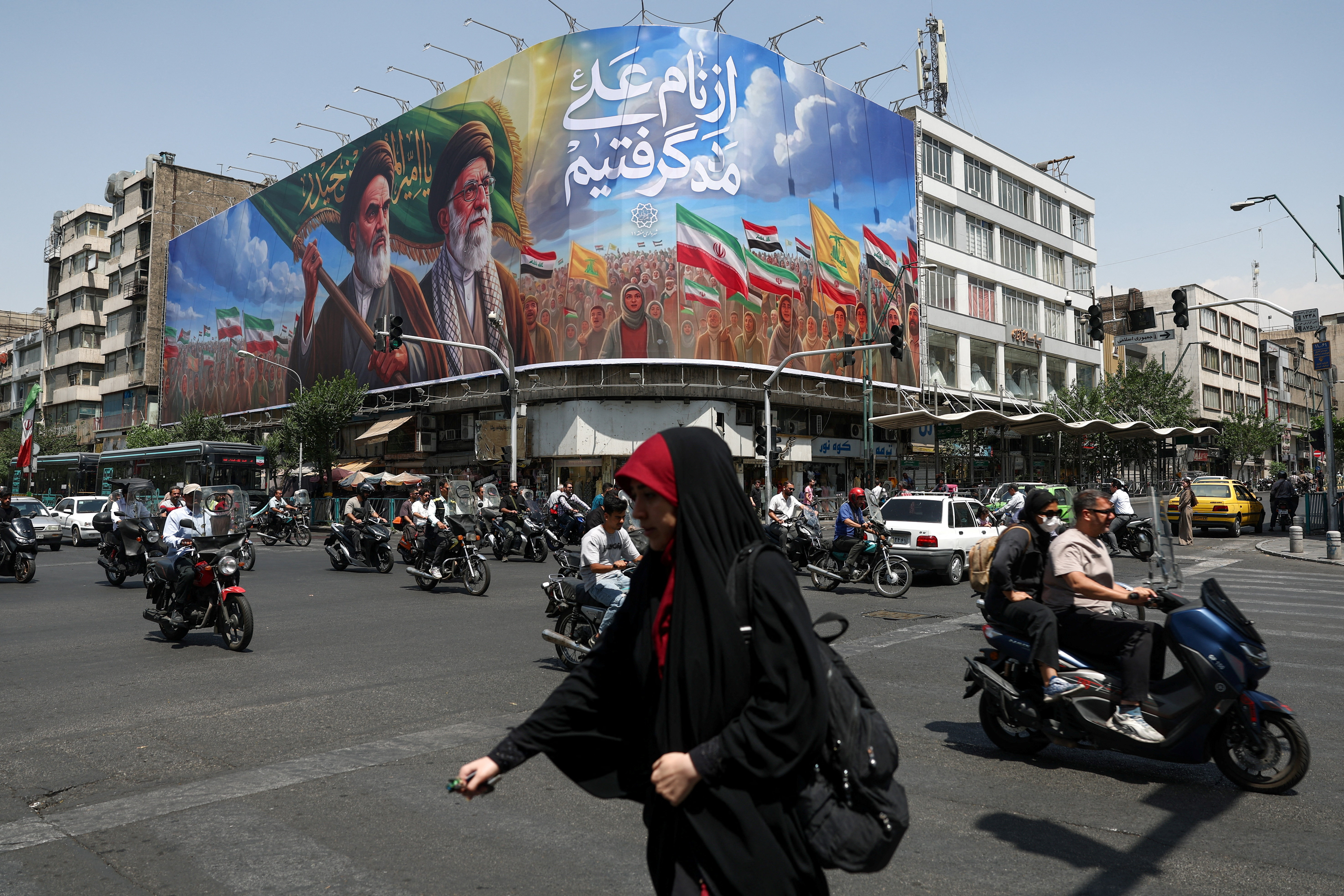 People ride past a billboard depicting the late leader of the Islamic Revolution