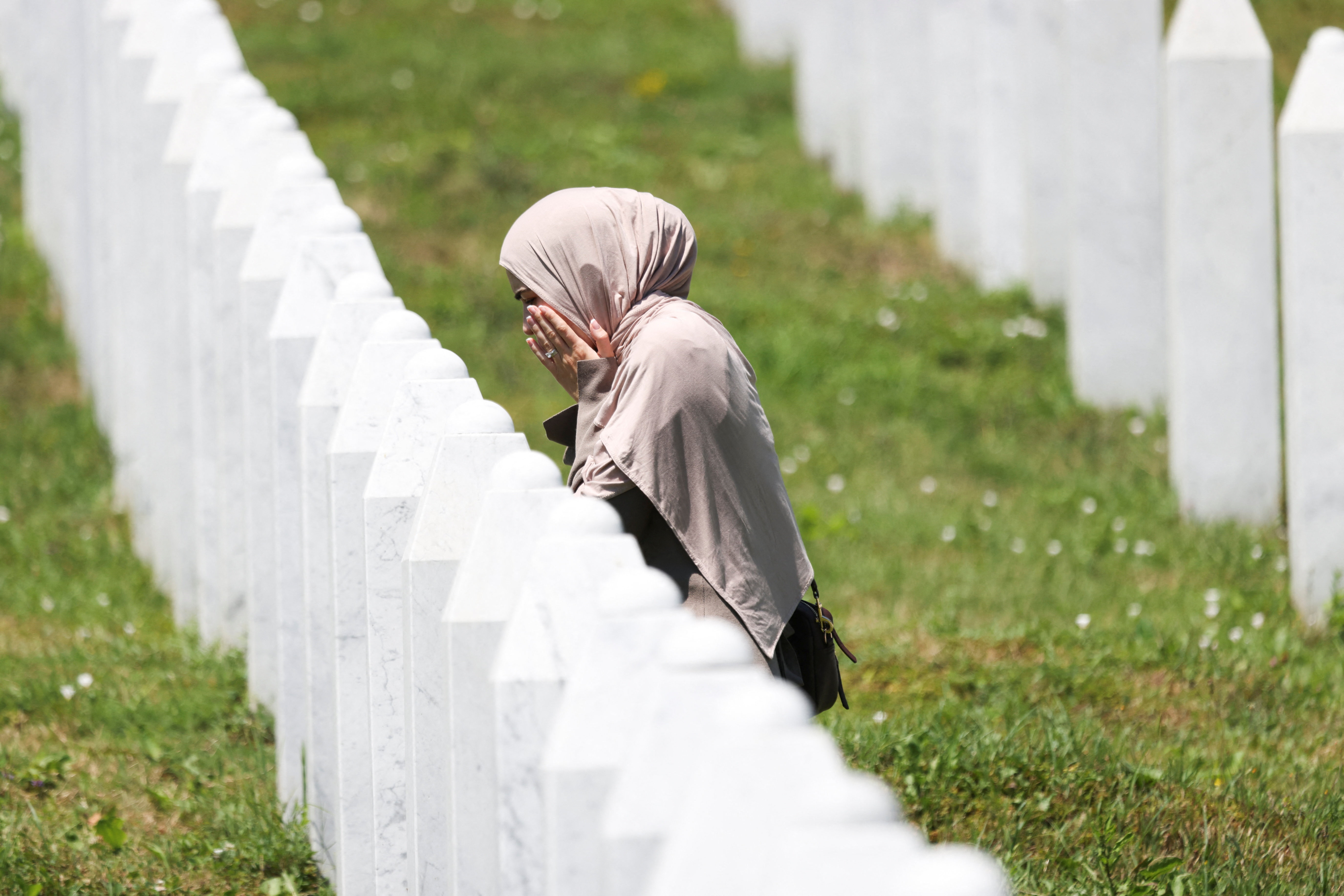 A Bosnian woman prays as she walks among gravestones of victims during preparations for the 31st anniversary of the Srebrenica genocide, in Potocari, Bosnia and Herzegovina, July 10, 2026. REUTERS/Amel Emric